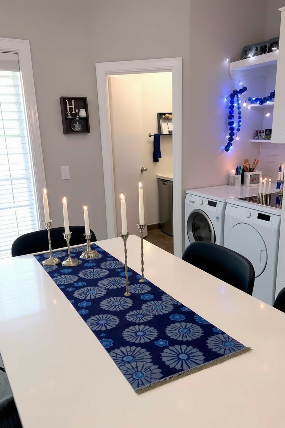 A festive table runner adorns a sleek workspace, featuring vibrant blue and silver patterns that evoke the spirit of celebration. The runner is complemented by neatly arranged candles and decorative elements that enhance the festive atmosphere. In the laundry room, Hanukkah decorations bring a touch of joy and warmth to the space. String lights in blue and white illuminate the area, while a small display of dreidels and menorahs adds a charming festive flair.