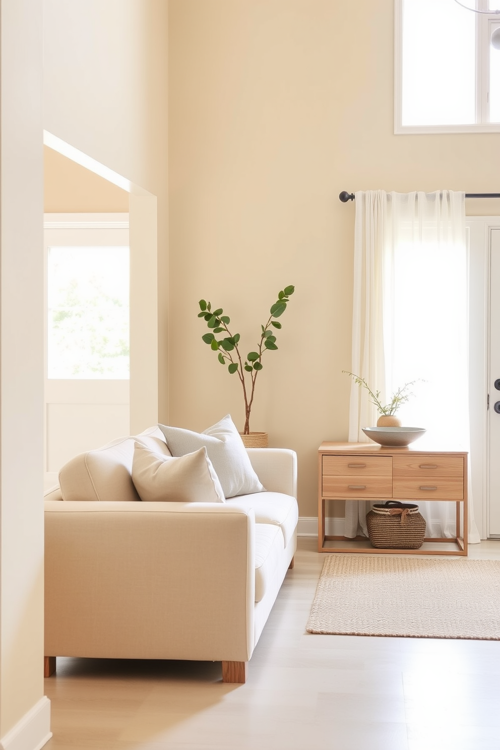 A serene living room entryway featuring a neutral color palette that evokes calmness. Soft beige walls provide a warm backdrop for a plush cream-colored sofa adorned with light gray throw pillows. A sleek console table made of light wood stands against the wall, topped with a decorative bowl and a small potted plant. Natural light filters in through sheer white curtains, illuminating the space and enhancing the tranquil atmosphere.