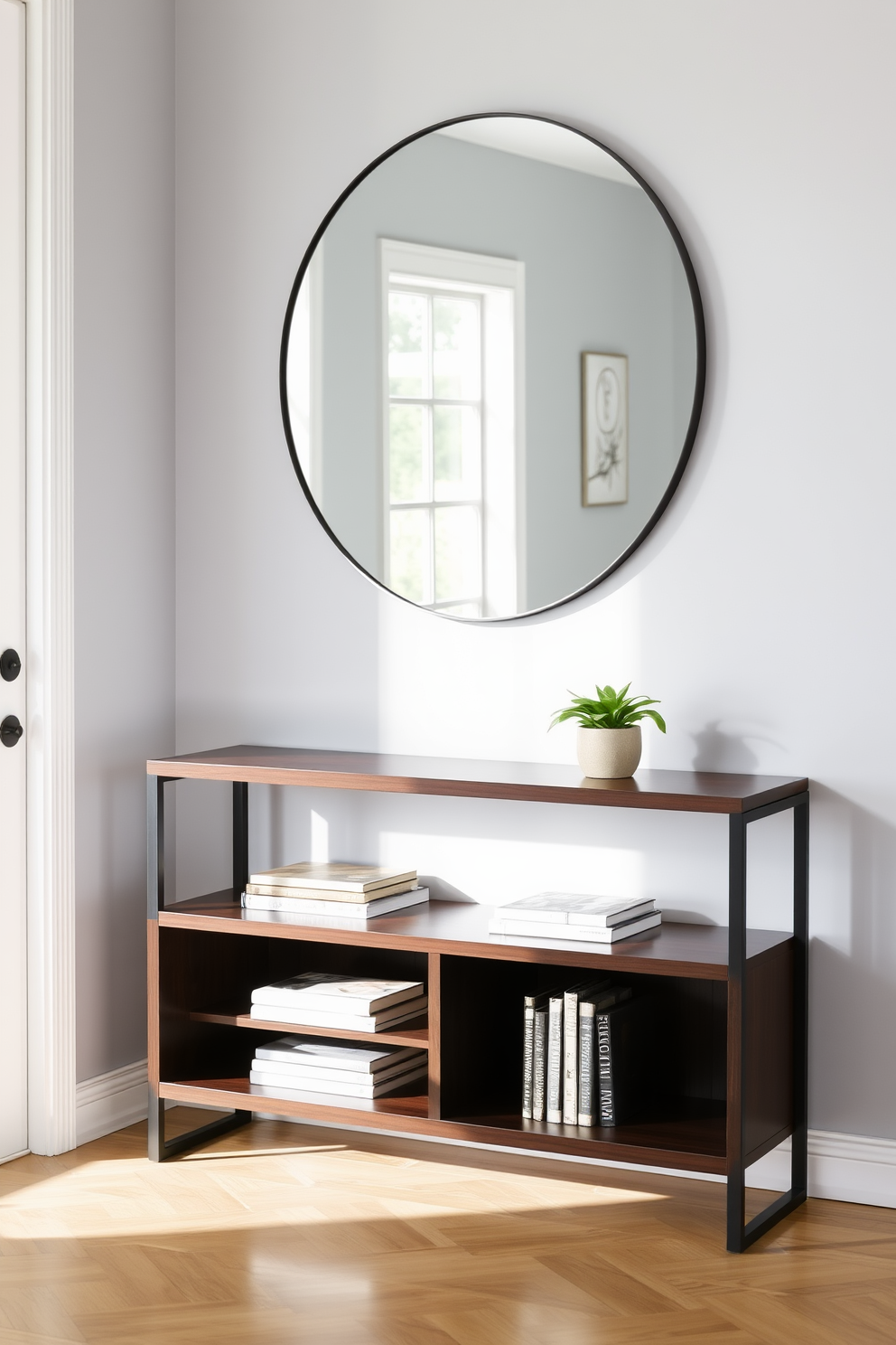 A stylish console table with storage is positioned against a light gray wall in the entryway. The table features a sleek design with a dark wood finish and integrated shelves for decorative items and books. Above the console table, a large round mirror reflects natural light from a nearby window. A small potted plant sits on the table, adding a touch of greenery and warmth to the space.