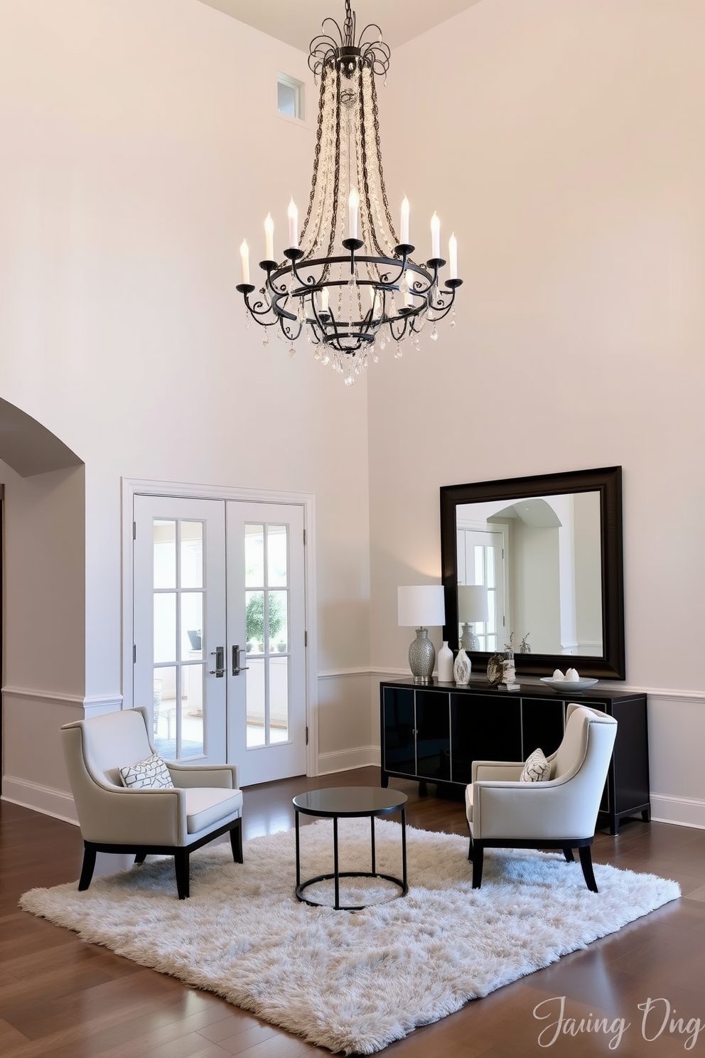 An elegant living room entryway features a stunning chandelier as the focal point. The chandelier hangs gracefully from a high ceiling, casting a warm glow over the space. Beneath the chandelier, a plush area rug defines the seating area, complemented by a pair of stylish armchairs. A sleek console table against the wall displays decorative items and a large mirror, enhancing the sense of space.