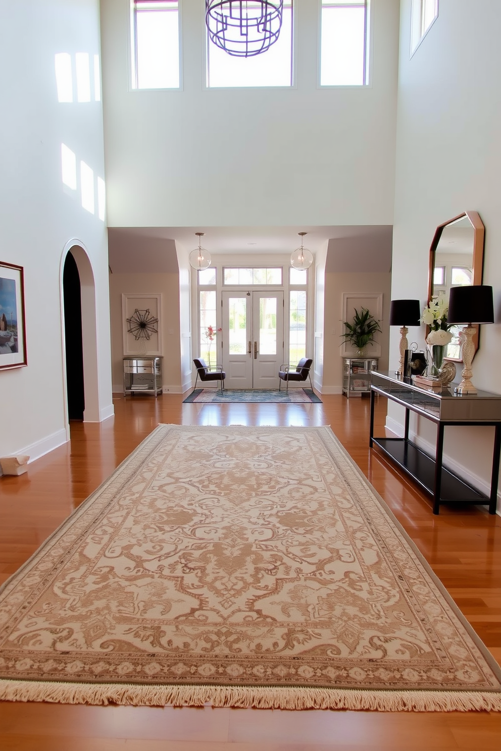 An elegant area rug anchors the space, featuring intricate patterns in soft, muted colors that complement the surrounding decor. The rug is placed centrally, creating a warm and inviting atmosphere in the room. The long foyer showcases a stunning design, with high ceilings and large windows allowing natural light to flood in. A sleek console table lines one wall, adorned with decorative items and a statement mirror above it, enhancing the sense of openness.