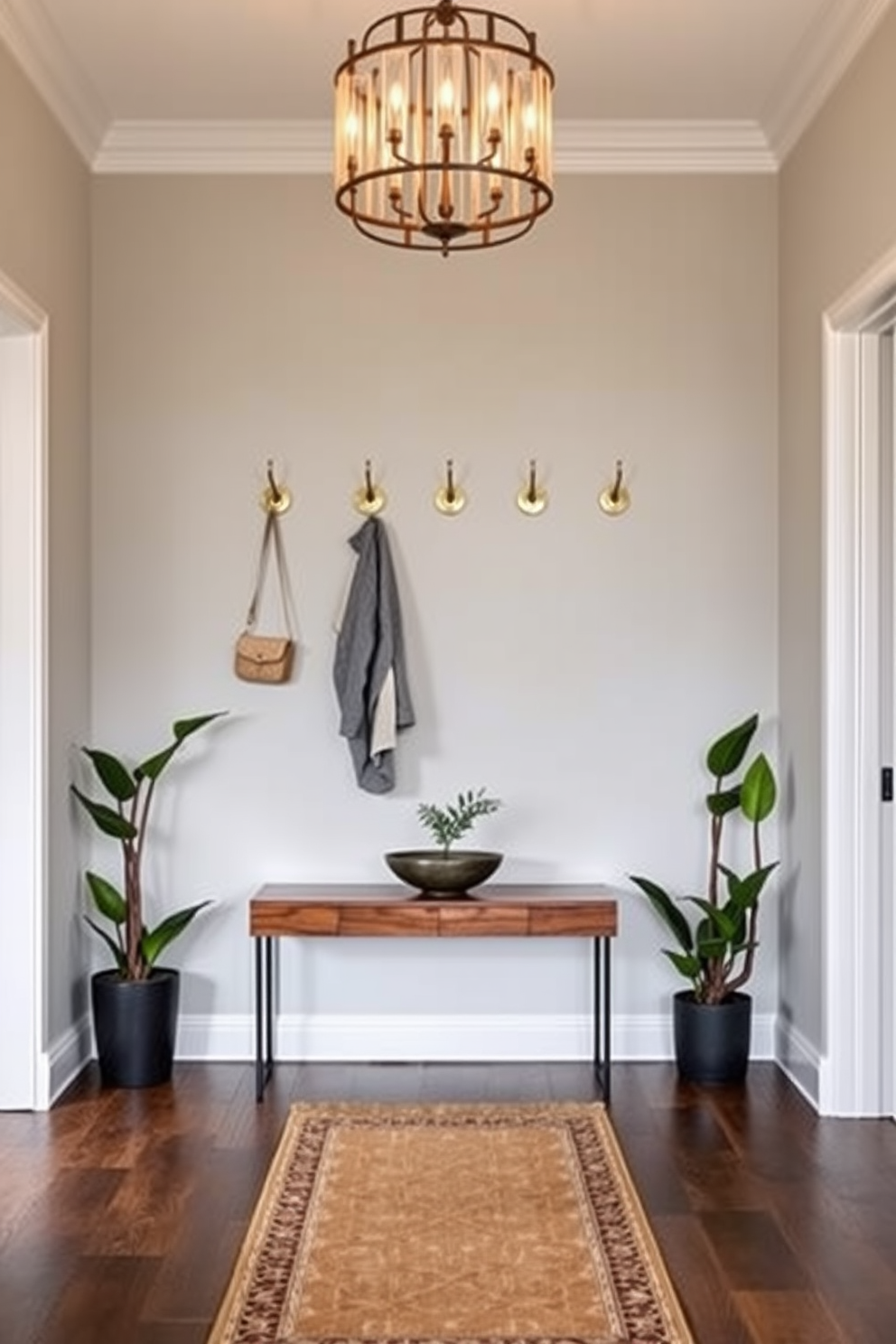 Decorative hooks for stylish organization. A row of elegantly designed hooks made from brushed brass is mounted on a soft gray wall, providing a chic way to hang coats and bags. Below, a sleek console table in rich walnut holds a decorative bowl and a small potted plant, adding warmth to the space. Long foyer design ideas. The foyer features an elongated layout with a stunning runner rug that guides guests through the space. Flanking the entrance, tall potted plants create a welcoming atmosphere, while a statement chandelier hangs above, casting a warm glow throughout.