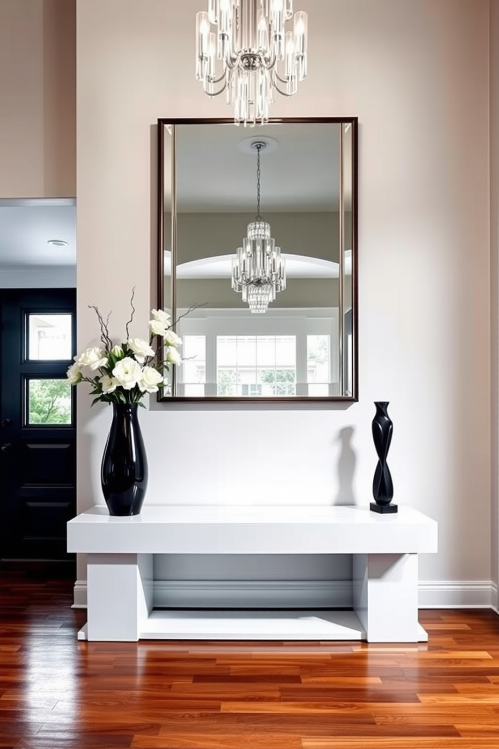 A sleek console table is positioned against a wall in a luxurious foyer. The table features a glossy finish and is adorned with decorative accents such as a tall vase filled with fresh flowers and a stylish sculpture. The foyer is illuminated by a stunning chandelier that hangs from a high ceiling. Rich hardwood flooring complements the elegant design, while a large mirror above the console table reflects the inviting ambiance.