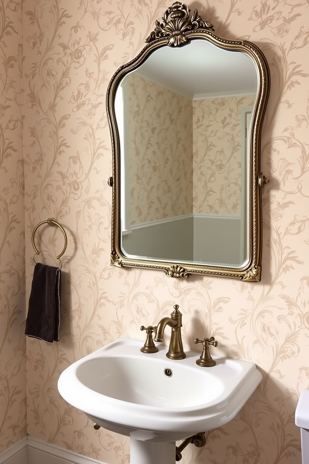 A vintage mirror with ornate frame details hangs above a sleek pedestal sink. The walls are adorned with elegant wallpaper featuring a subtle floral pattern, complemented by antique brass fixtures.