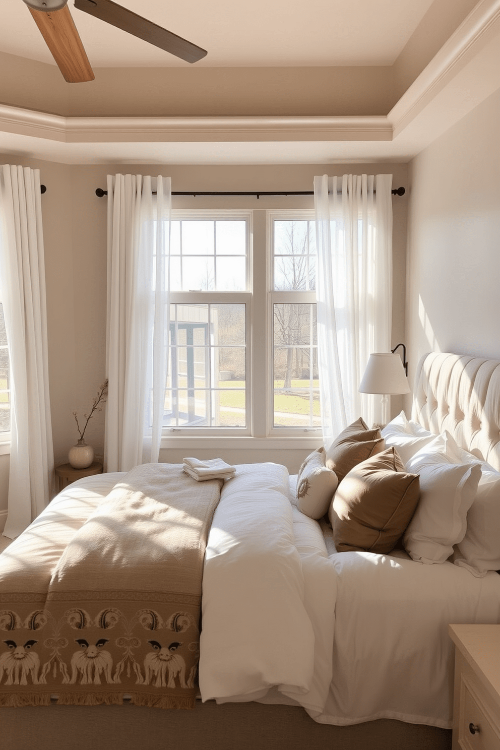 A cozy master bedroom adorned with a neutral color palette that promotes serenity. Soft beige walls complement a plush cream upholstered headboard, while warm wooden accents add a touch of natural elegance. The bedding features layers of fluffy white and taupe linens, creating an inviting atmosphere. Large windows allow natural light to flood the space, framed by sheer white curtains that gently sway with the breeze.