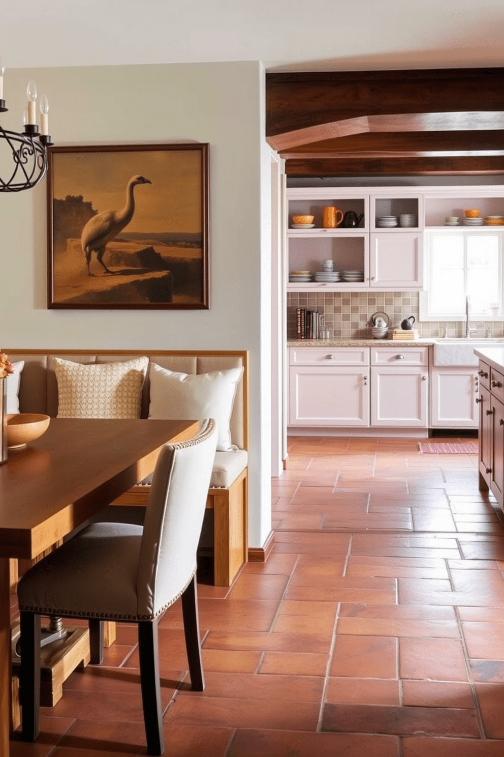 A built-in banquette with plush cushions creates a cozy dining space. The table is surrounded by natural wood accents and features a warm, inviting color palette. In the Mediterranean kitchen, terracotta tiles line the floor, adding rustic charm. The cabinetry is painted in soft pastel hues, complemented by open shelving displaying colorful dishware.