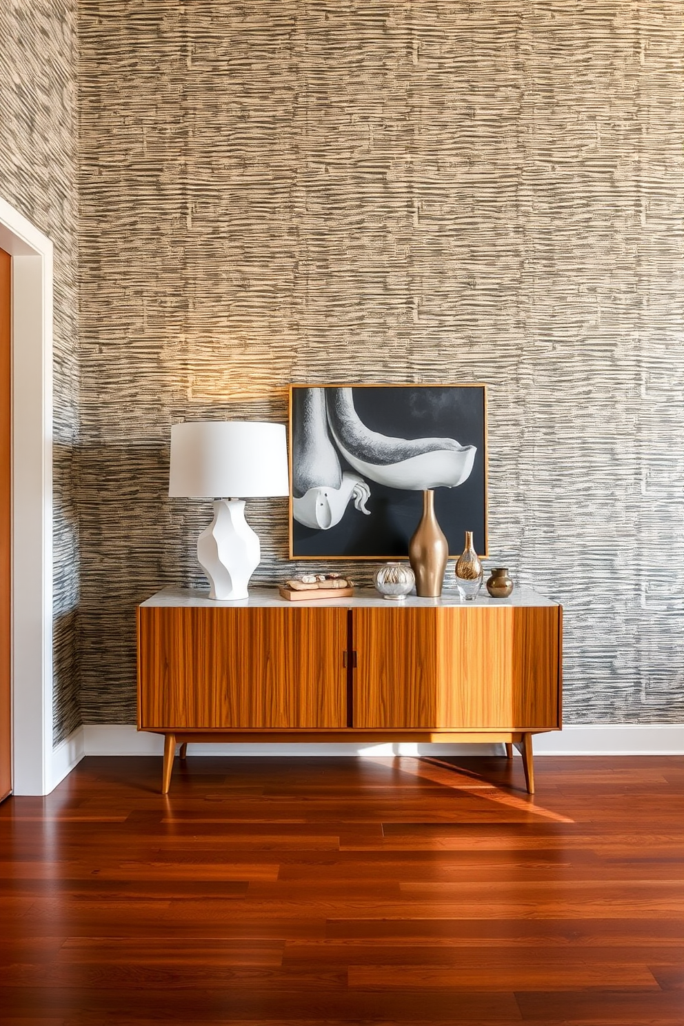 A Mid Century Modern foyer features textured wallpaper that adds depth and visual interest to the space. The flooring is made of rich hardwood, complemented by a statement console table adorned with a sculptural lamp and decorative objects.