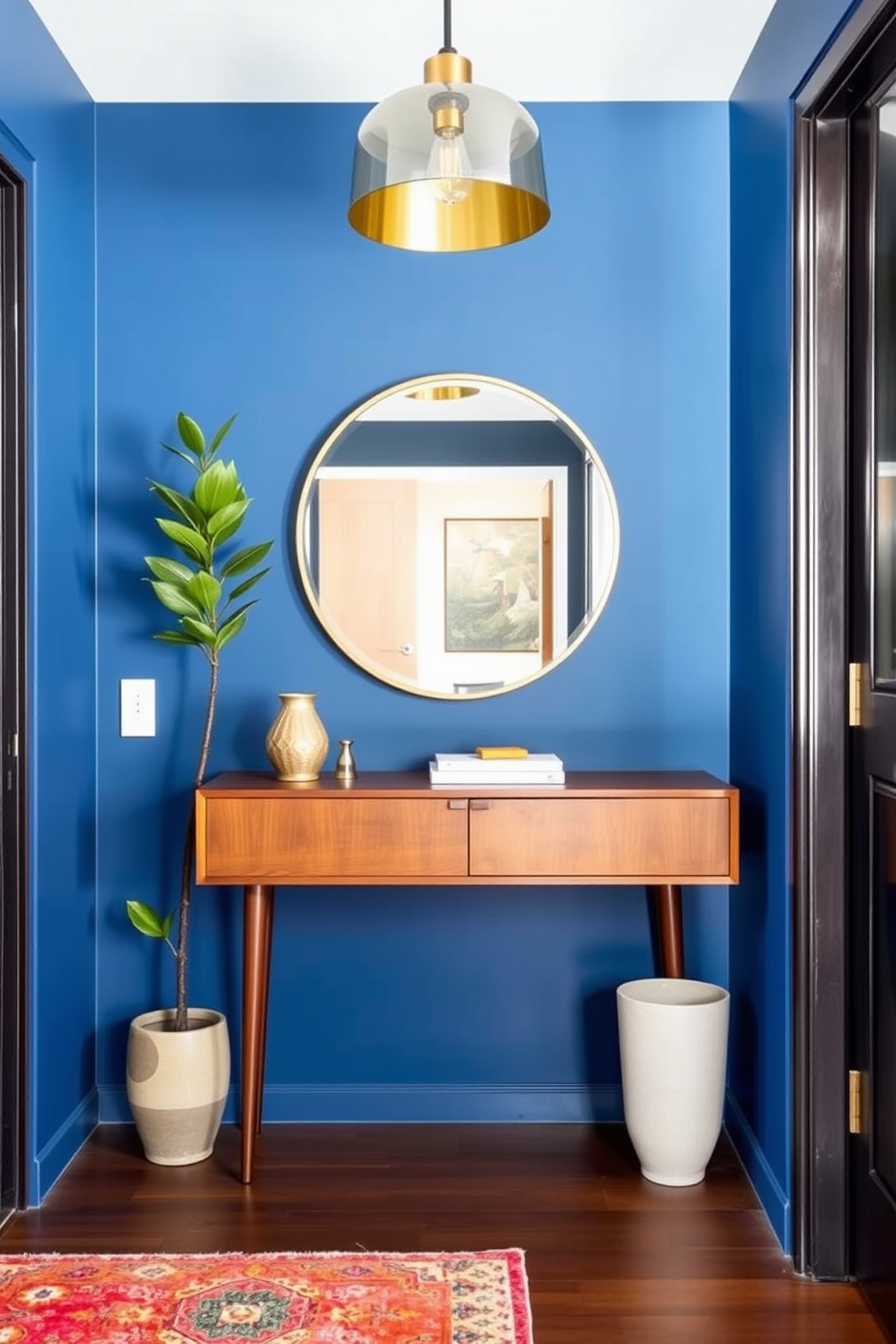 A striking foyer features an accent wall painted in a bold deep blue that draws the eye immediately upon entry. The space is adorned with a sleek console table made of walnut, complemented by a large round mirror with a brass frame above it. To the left, a vibrant area rug adds warmth and texture, while a tall indoor plant in a ceramic pot brings a touch of nature indoors. The lighting is provided by a stylish pendant light fixture that enhances the Mid Century Modern aesthetic of the space.