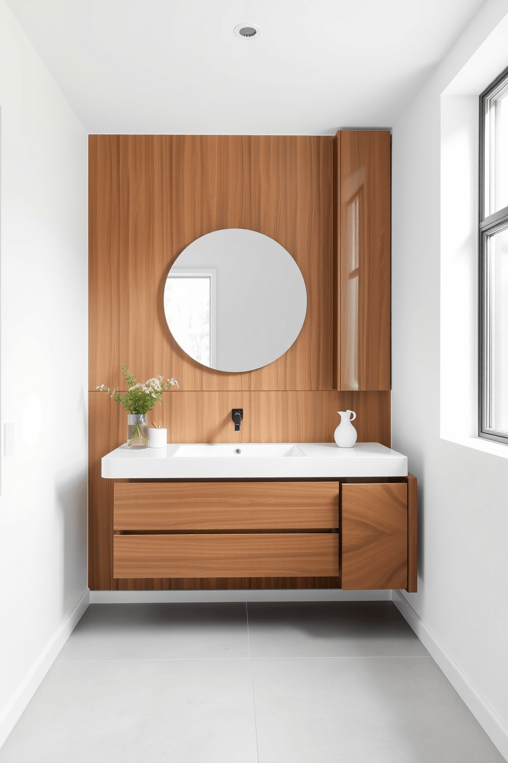 Sleek floating vanity with clean lines is the focal point of the minimalist bathroom. The walls are painted in a soft white hue, enhancing the sense of space and tranquility. Large format tiles in a light gray cover the floor, adding a modern touch. A simple round mirror hangs above the vanity, reflecting natural light from a nearby window.