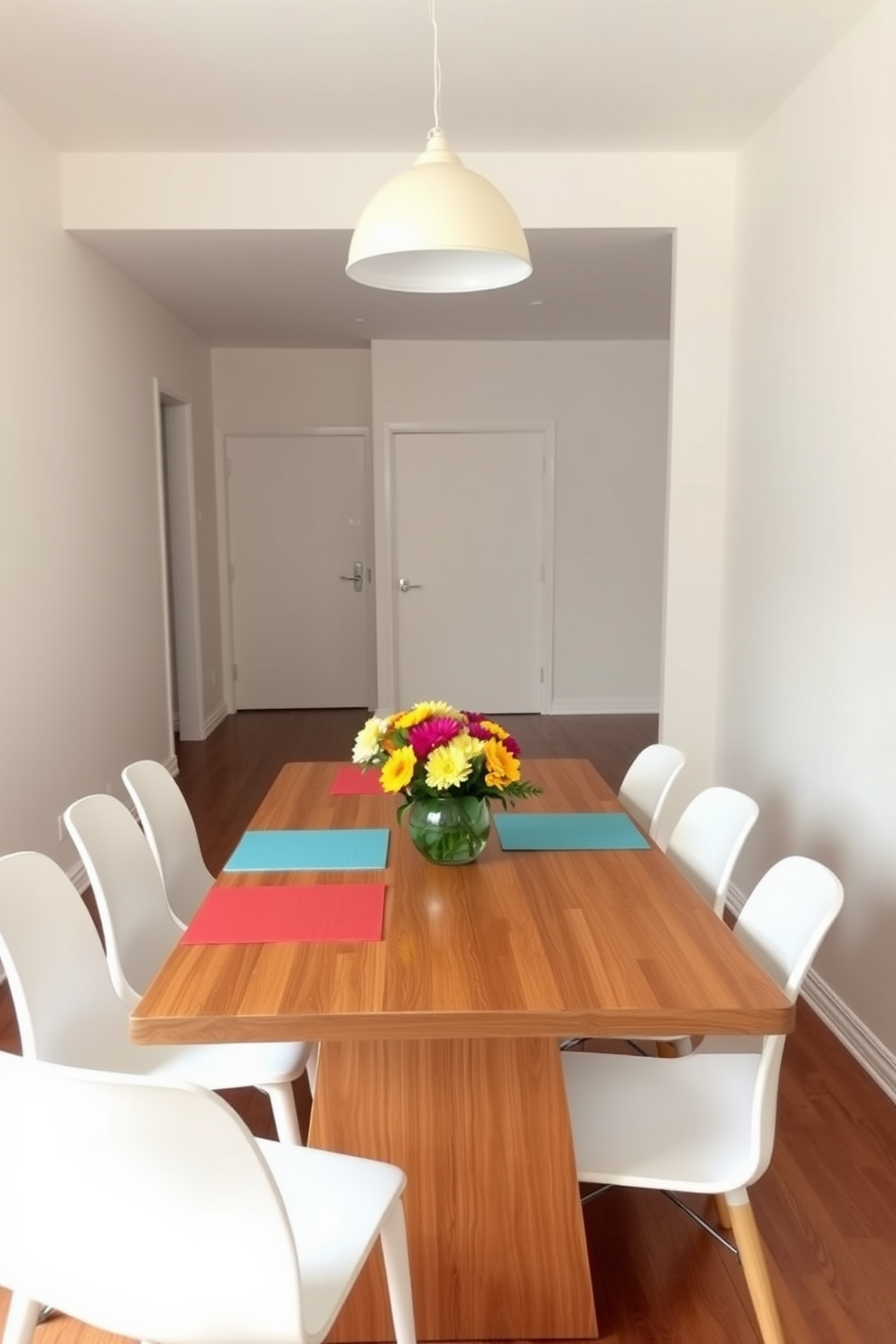 A minimalist dining room features a sleek wooden table surrounded by white chairs. Color pops through minimal accessories like a vibrant centerpiece and colorful placemats. The walls are painted in a soft neutral tone, creating a calm atmosphere. A simple pendant light hangs above the table, adding a touch of elegance without overwhelming the space.