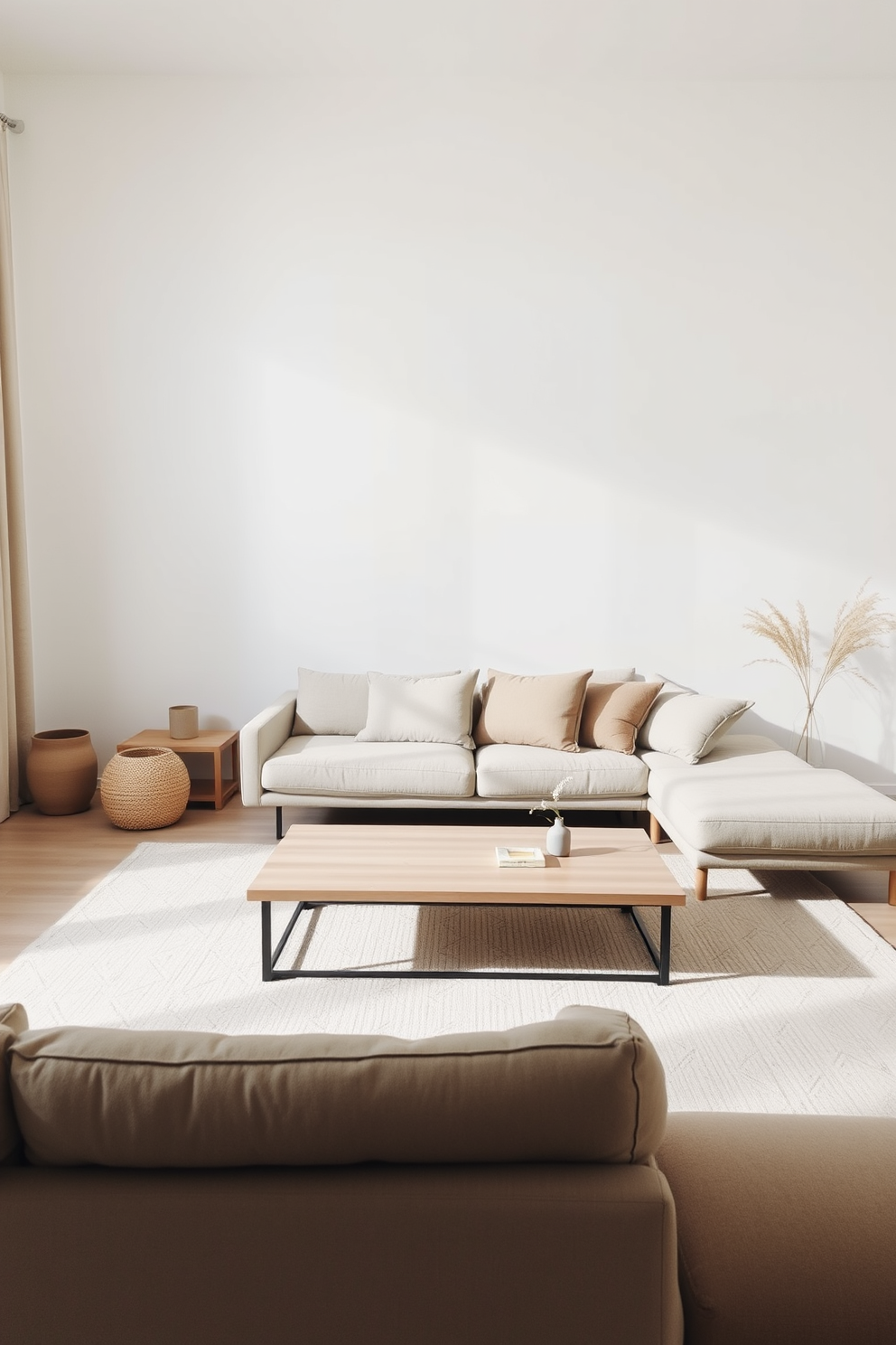 A minimalist living room featuring a neutral color palette with a focus on simplicity and functionality. The space includes a low-profile sofa adorned with soft, textured cushions and a sleek coffee table made of light wood. The walls are painted in a soft white hue, creating an airy atmosphere. A large area rug with a subtle geometric pattern anchors the seating area, while a few carefully selected decorative items add personality without cluttering the space.