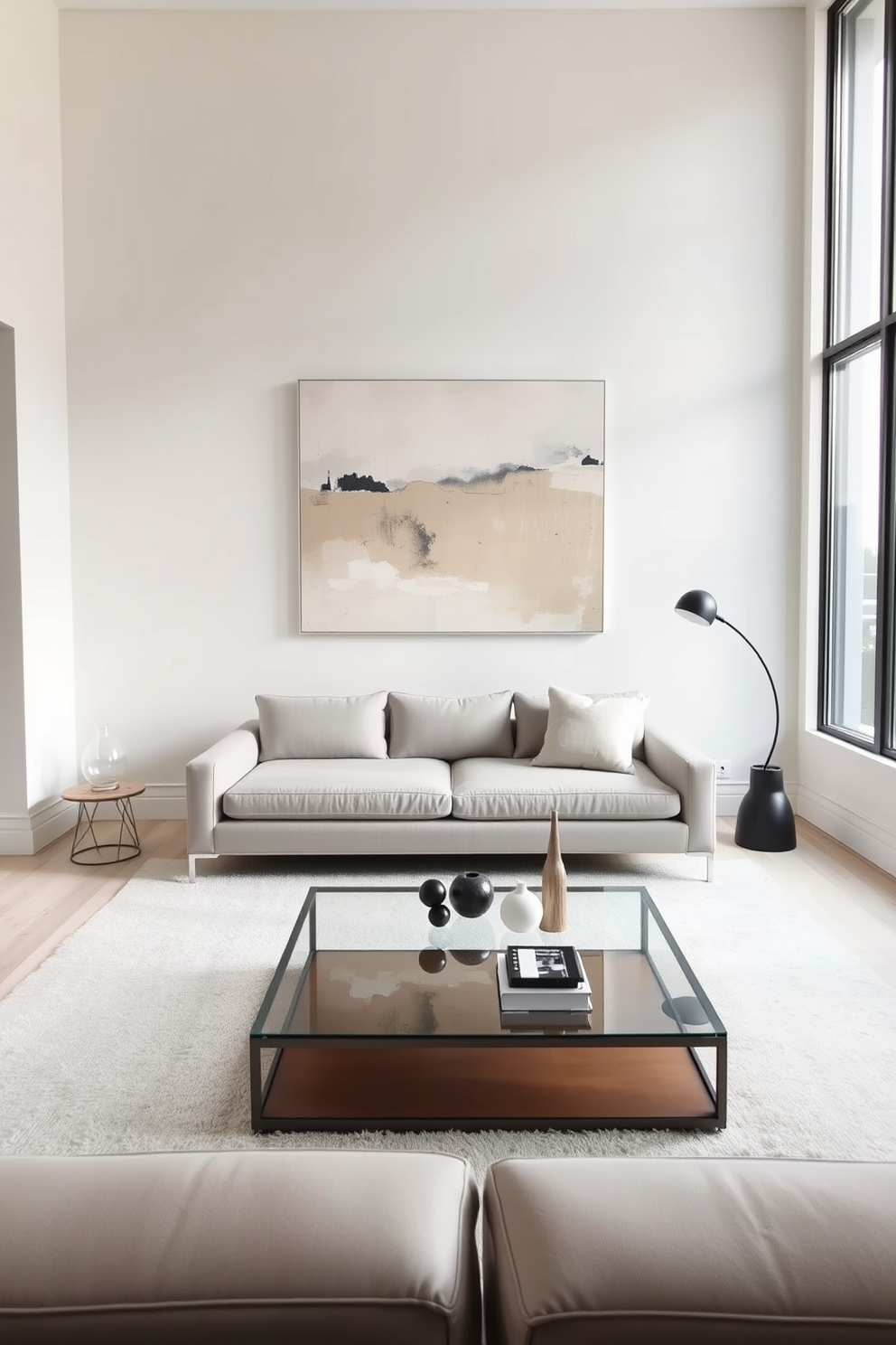 A minimalist living room featuring sleek furniture and clean lines. The color palette consists of soft neutrals, with a large abstract art piece in muted tones hanging above a low-profile sofa. A simple coffee table made of glass and metal sits at the center, surrounded by a few carefully chosen decorative items. Natural light floods the space through large windows, highlighting the airy feel of the room.