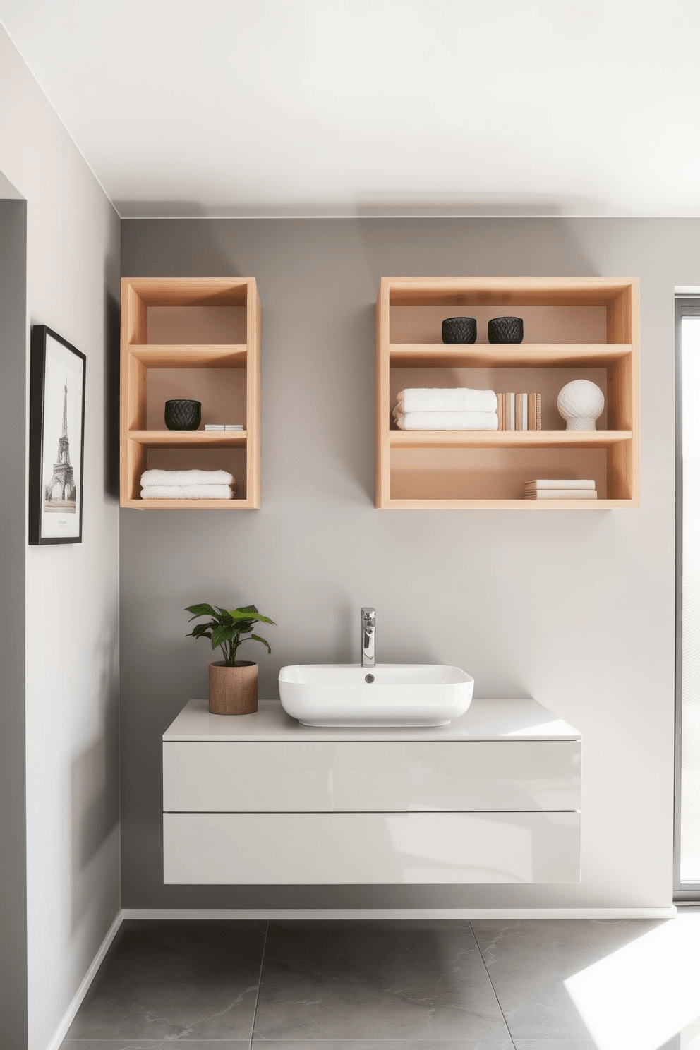 Open shelving units made of light wood are mounted on the walls, showcasing neatly arranged towels and decorative items. Below, a sleek floating vanity with a white sink complements the minimalist aesthetic, while the walls are painted in a soft gray hue. Large format tiles in a glossy finish cover the floor, reflecting natural light that streams in through a frosted glass window. A potted plant sits on the open shelf, adding a touch of greenery to the modern bathroom space.