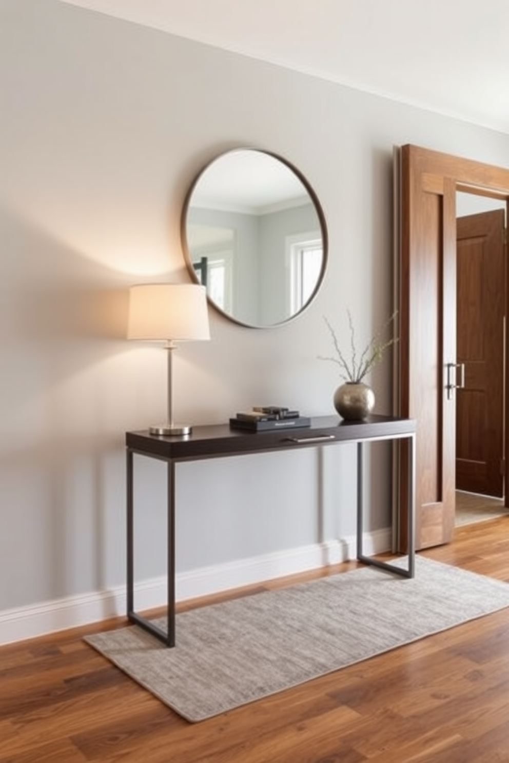 A sleek console table stands against a light gray wall, adorned with a few carefully selected decorative items. A simple, elegant lamp and a small potted plant add a touch of greenery, while a large round mirror above the table enhances the sense of space. The entryway features a neutral color palette with warm wood accents, creating a welcoming atmosphere. A stylish rug in muted tones lies beneath the console, providing a cozy contrast to the polished hardwood floor.