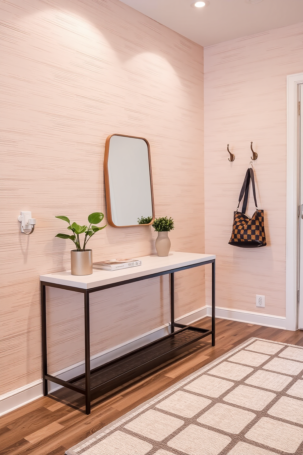 Textured wallpaper in soft neutral tones creates a warm and inviting atmosphere in a modern entryway. A sleek console table with a minimalist design is positioned against the wall, topped with a decorative mirror and a small potted plant for added charm. The entryway features a geometric patterned rug that adds depth and character to the space. Stylish wall hooks made of brushed metal are mounted nearby, providing a functional yet elegant touch for hanging coats and bags.