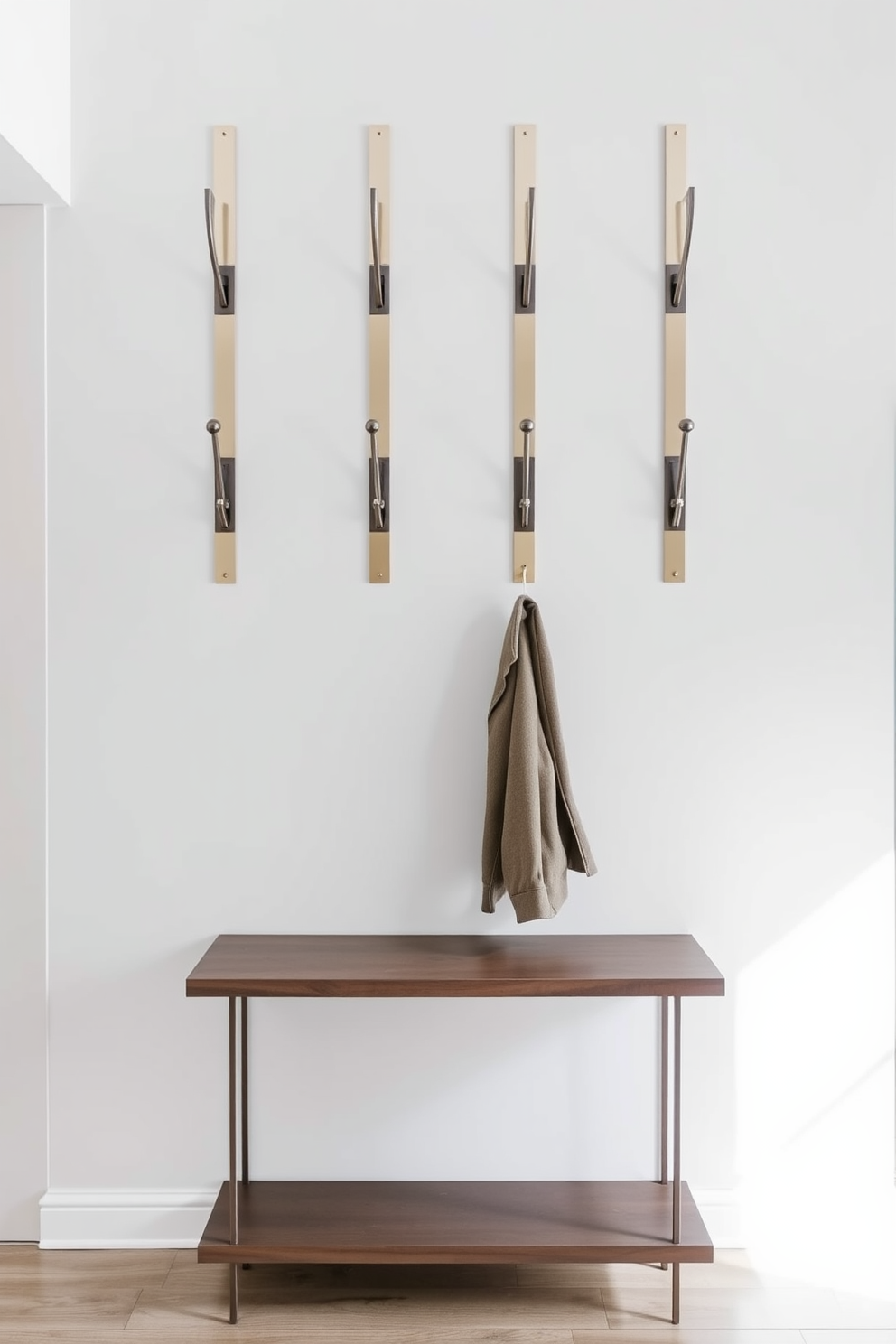 A modern entryway features sleek wall-mounted coat hooks arranged in a stylish pattern. The walls are painted in a light gray hue, complemented by a minimalist console table beneath the hooks.