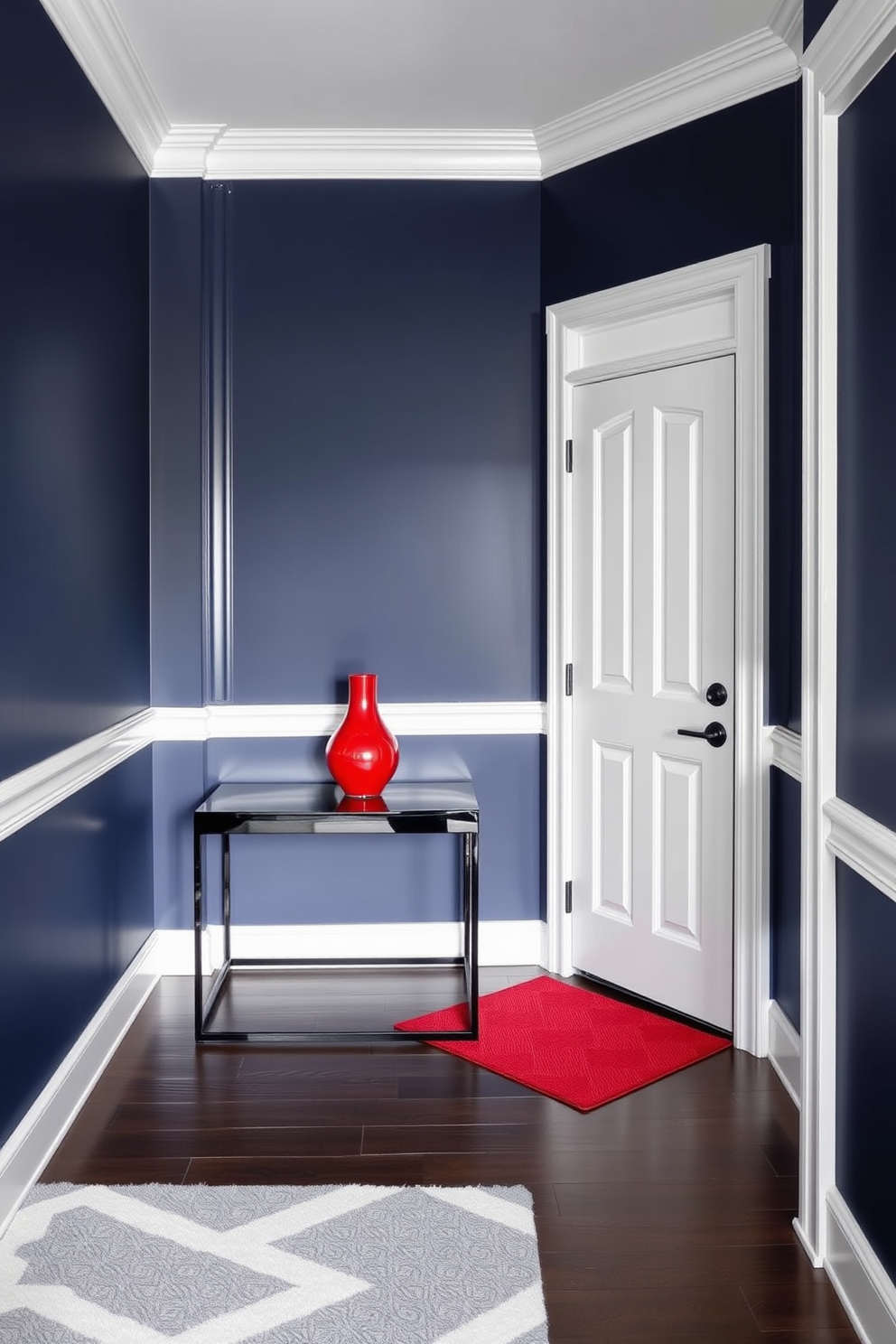 A striking entryway featuring high-contrast colors that create a bold statement. The walls are painted in a deep navy blue while the trim and door are a crisp white, enhancing the dramatic effect. A sleek console table in a glossy black finish sits against the wall, topped with a vibrant red vase. The floor is adorned with a geometric patterned rug in shades of gray and white, adding texture and interest to the space.