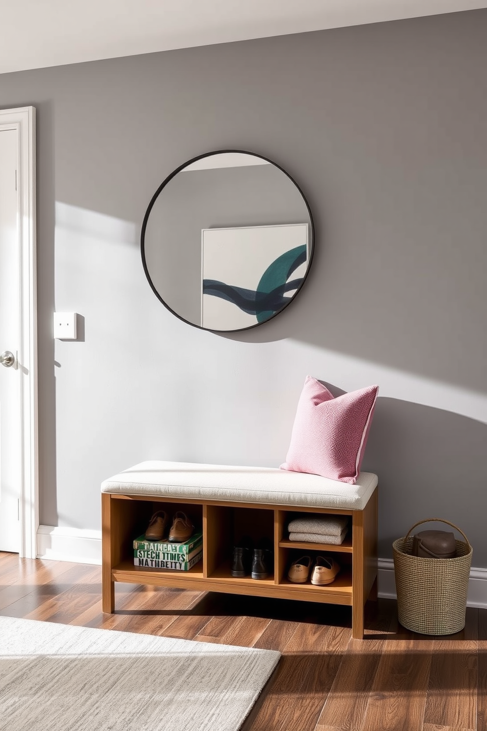 A stylish bench with hidden storage options is positioned against the wall in a modern entryway. The bench features a sleek design with a soft upholstered seat and a minimalist wooden frame, providing both functionality and aesthetic appeal. Above the bench, a large round mirror reflects natural light, enhancing the spacious feel of the entryway. The walls are painted in a soft gray tone, complemented by a contemporary artwork piece that adds a pop of color.