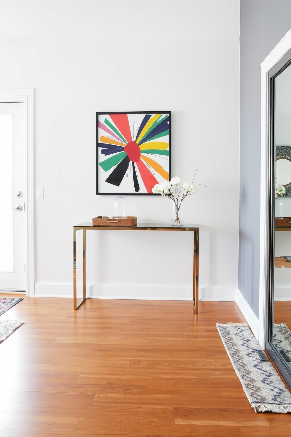 A modern foyer featuring a sleek console table made of glass and metal. Bold artwork hangs prominently on the wall, drawing the eye with its vibrant colors and dynamic shapes. The flooring is a polished hardwood that complements the contemporary aesthetic. A stylish area rug adds warmth and texture, while a decorative mirror enhances the sense of space and light.