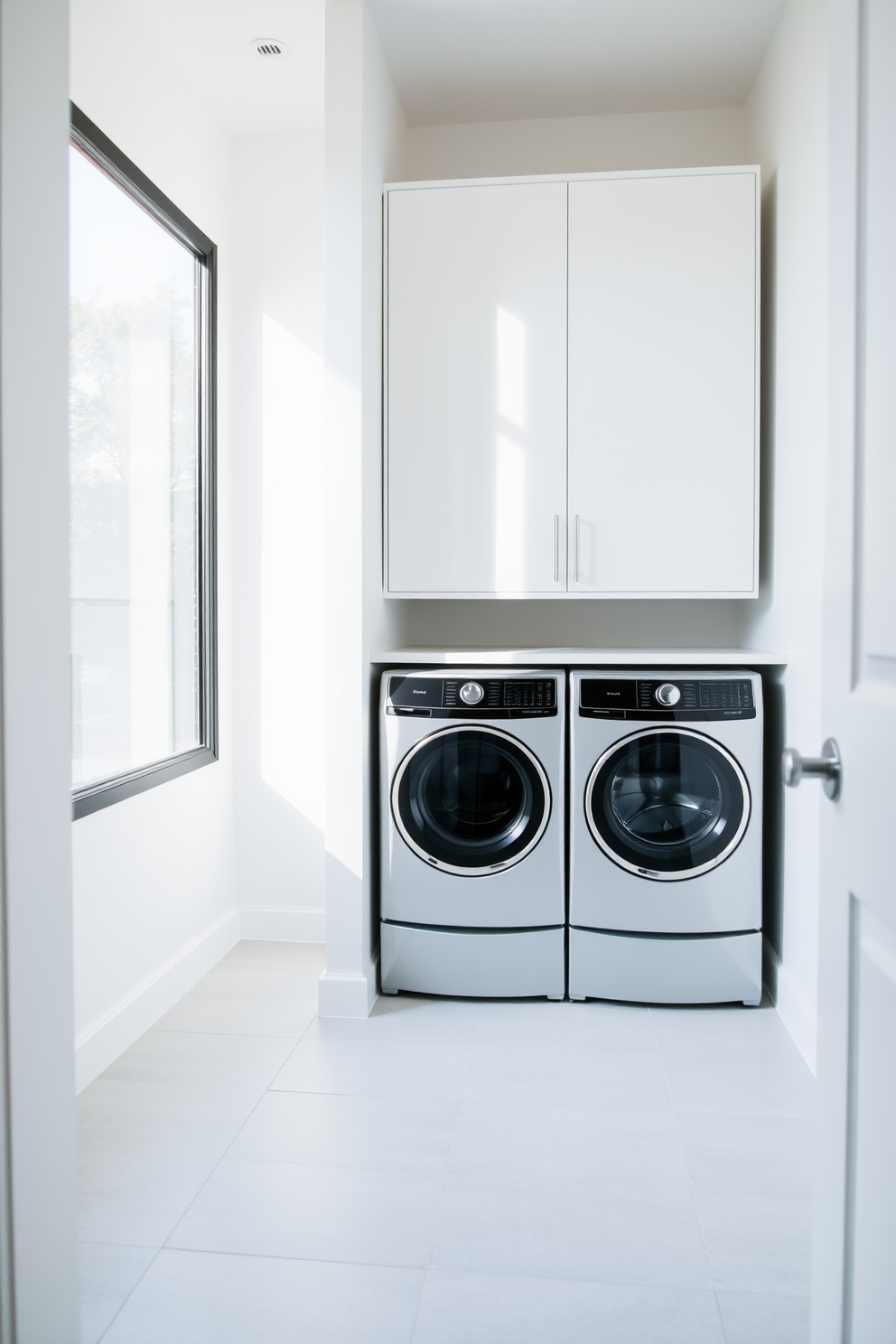 A minimalist laundry room featuring sleek appliances and a streamlined layout. The walls are painted in a soft white hue, and the floor is covered with light gray tiles for a clean look. A built-in washer and dryer are seamlessly integrated into cabinetry, providing ample storage space. Natural light floods the room through a large window, enhancing the airy and uncluttered atmosphere.