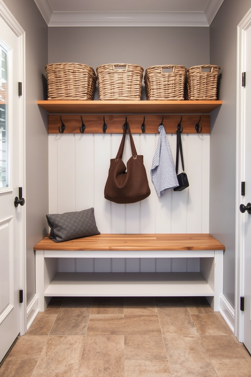 A compact mudroom design featuring fold-down seating that maximizes space efficiency. The walls are painted in a soft gray, and the floor is covered with durable, textured tiles for easy maintenance. The fold-down bench is crafted from reclaimed wood, providing a rustic touch while saving space. Above the seating, open shelving displays neatly organized baskets for storage and hooks for hanging coats and bags.