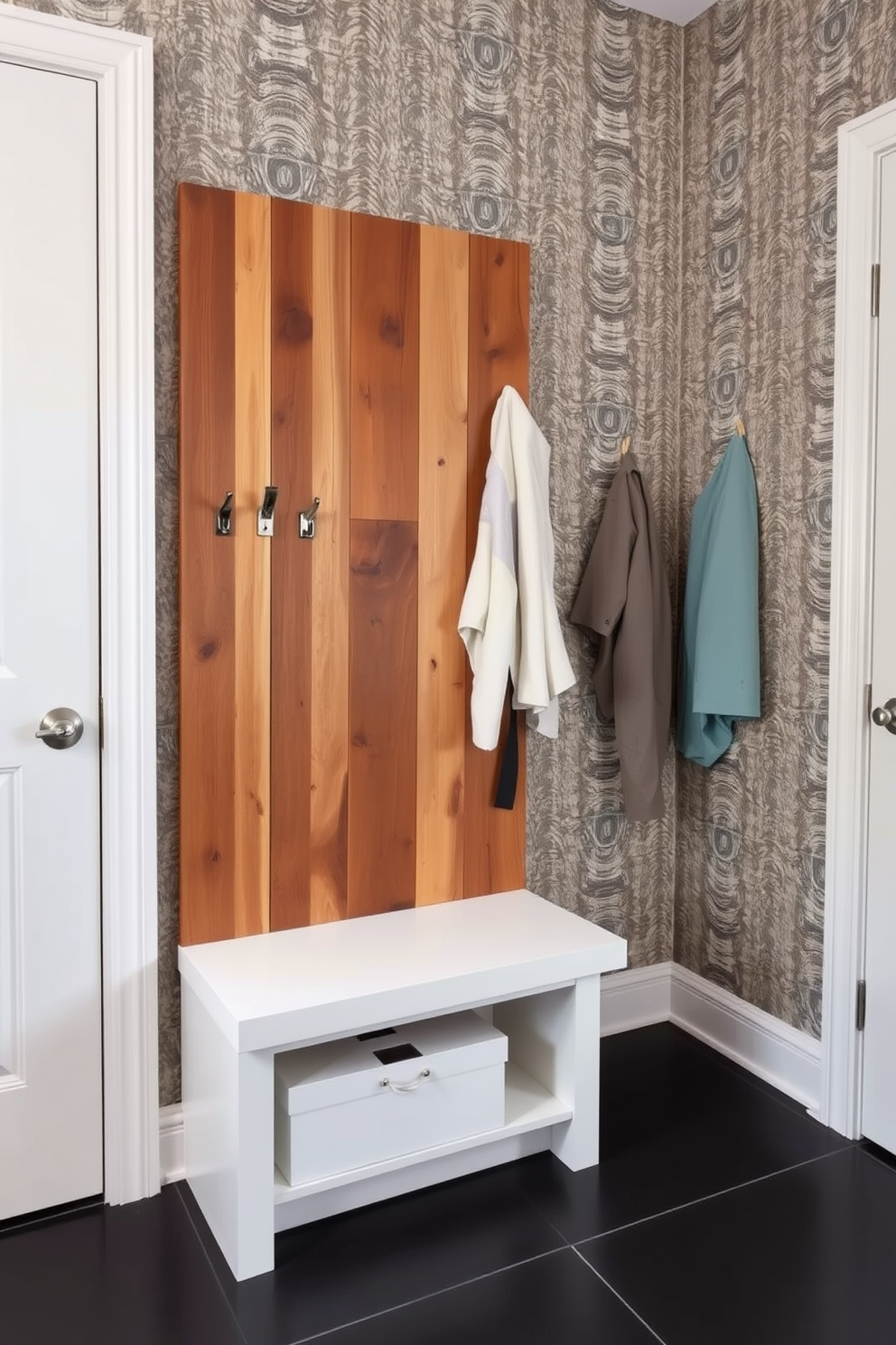 A stylish coat rack made of reclaimed wood stands against a wall adorned with textured wallpaper. The rack features unique metal hooks in various shapes, providing a functional yet artistic touch to the space. In the modern mudroom, a sleek bench with built-in storage complements the coat rack. The floor is covered with large, dark tiles that contrast beautifully with the light color scheme of the room.