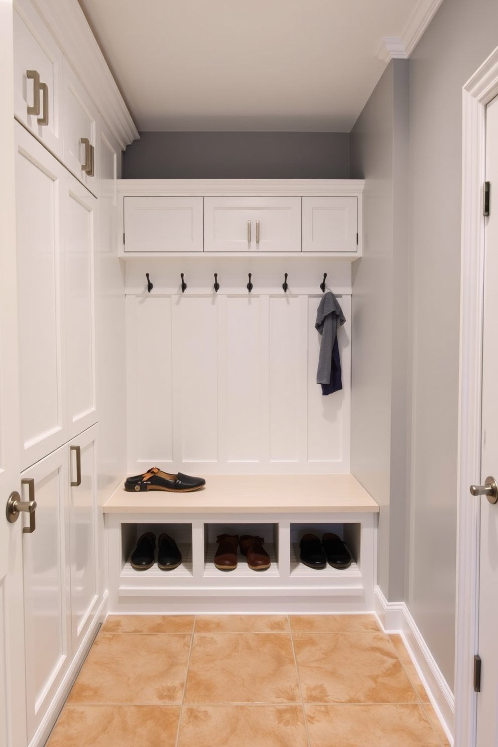 Functional lockers for organized family gear. The mudroom features built-in lockers with individual compartments for each family member, finished in a crisp white with brushed nickel hardware. A spacious bench sits below a row of hooks, providing a comfortable spot to sit while putting on or taking off shoes. The walls are painted in a soft gray, and the floor is covered with durable, water-resistant tiles in a warm beige tone.