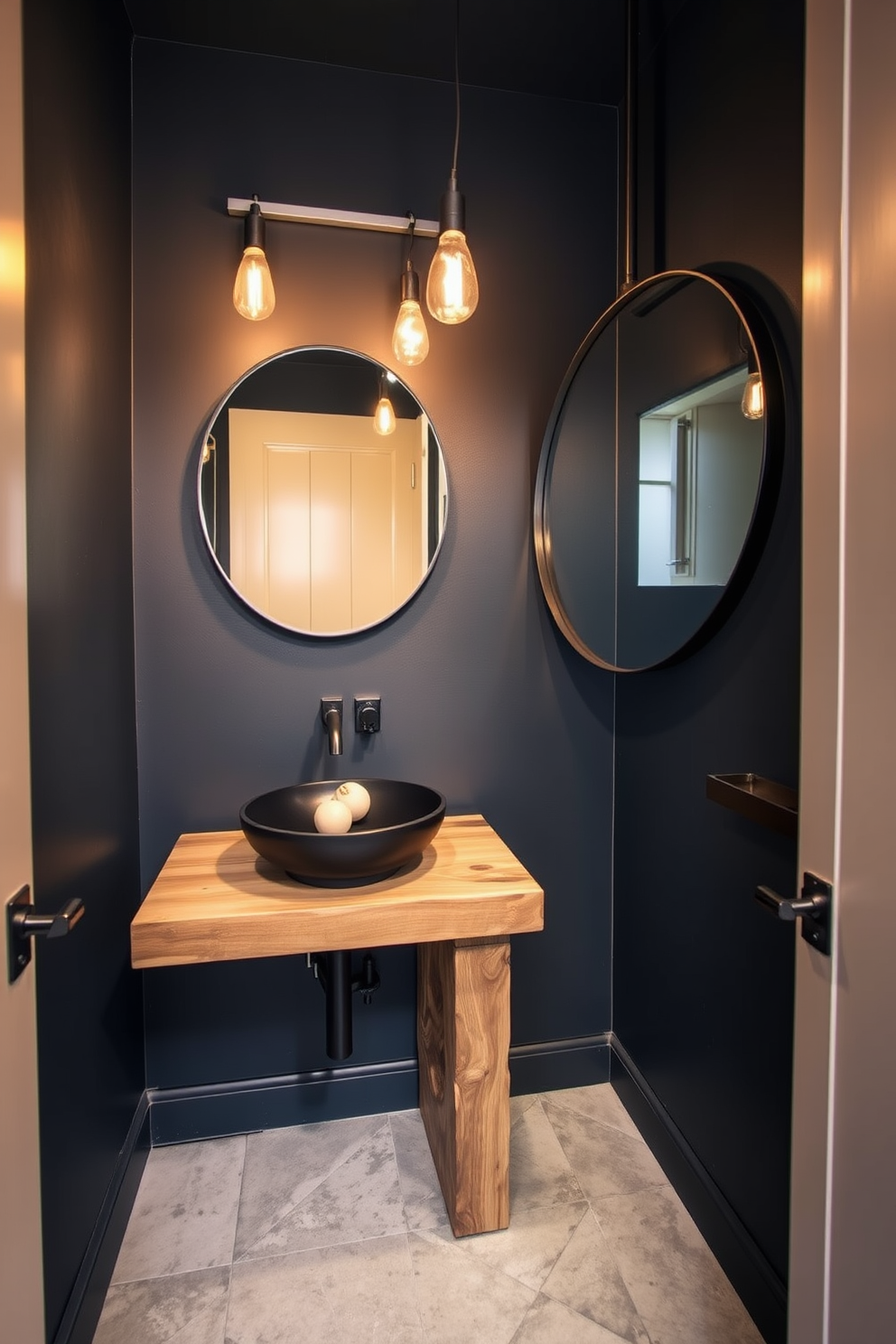 A modern powder room features industrial-style fixtures that create a trendy and chic atmosphere. The walls are painted in a deep charcoal color, and the lighting consists of exposed Edison bulbs hanging from a metal frame. A sleek black sink is mounted on a reclaimed wood vanity, adding warmth to the industrial elements. The floor is adorned with large concrete tiles, and a large round mirror with a black metal frame reflects the stylish design.