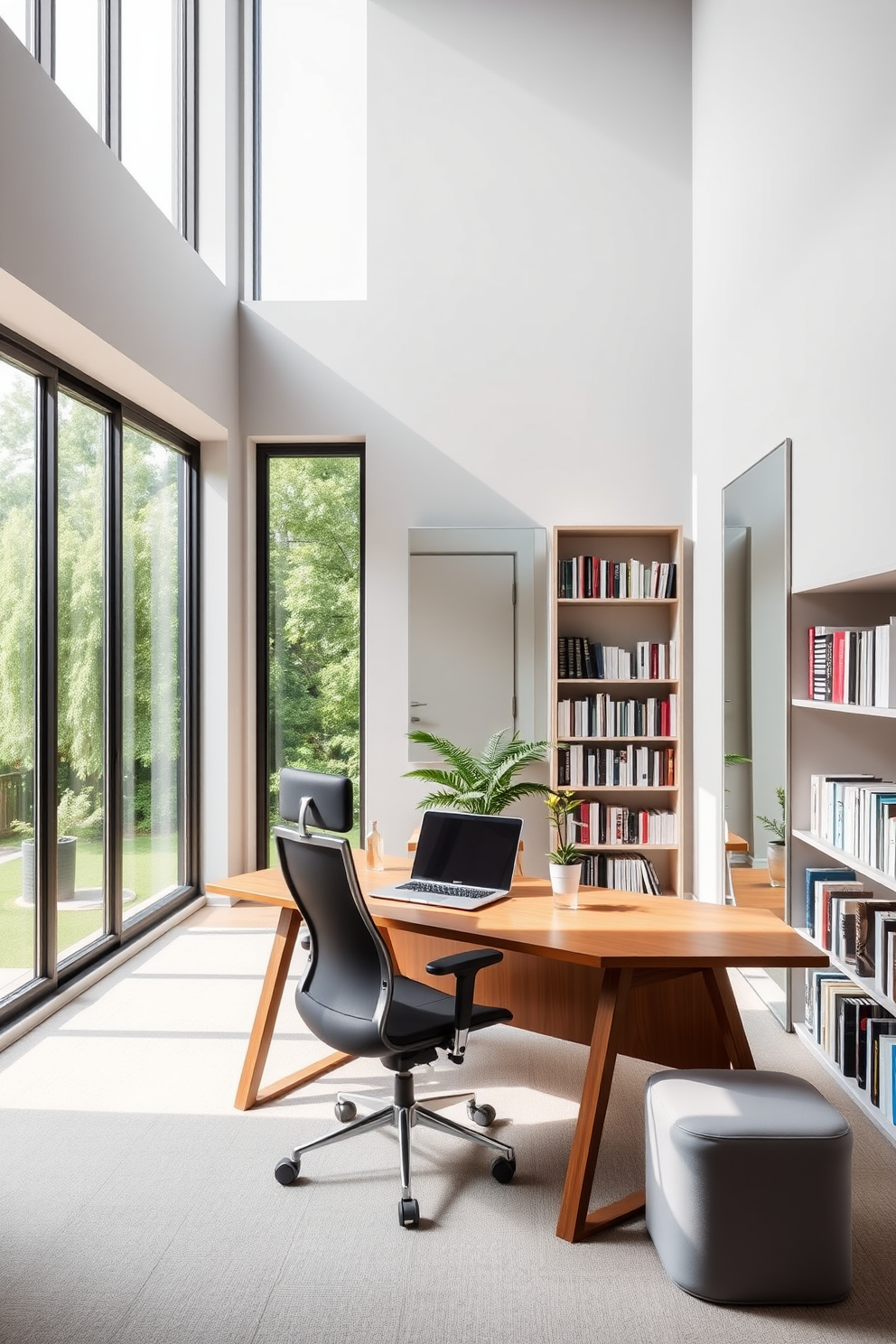 A modern study room featuring large windows that allow natural light to flood the space. The walls are painted in a soft gray, and a sleek wooden desk is positioned in front of the windows, complemented by a comfortable ergonomic chair. On the desk, a stylish laptop sits next to a small potted plant, adding a touch of greenery. A large wall-mounted mirror reflects the light and creates an illusion of more space, while bookshelves filled with neatly arranged books line the opposite wall.