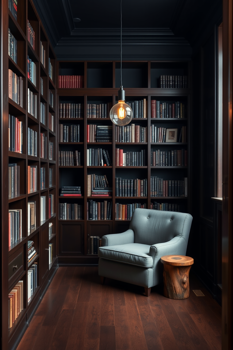 A moody home library with rich dark wood bookshelves that reach from floor to ceiling. The walls are painted in a deep navy blue, creating an intimate and cozy atmosphere. A large, plush armchair in a soft gray fabric is positioned in the corner, accompanied by a small side table made of reclaimed wood. A warm, ambient light fixture hangs from the ceiling, casting a gentle glow over the reading nook.