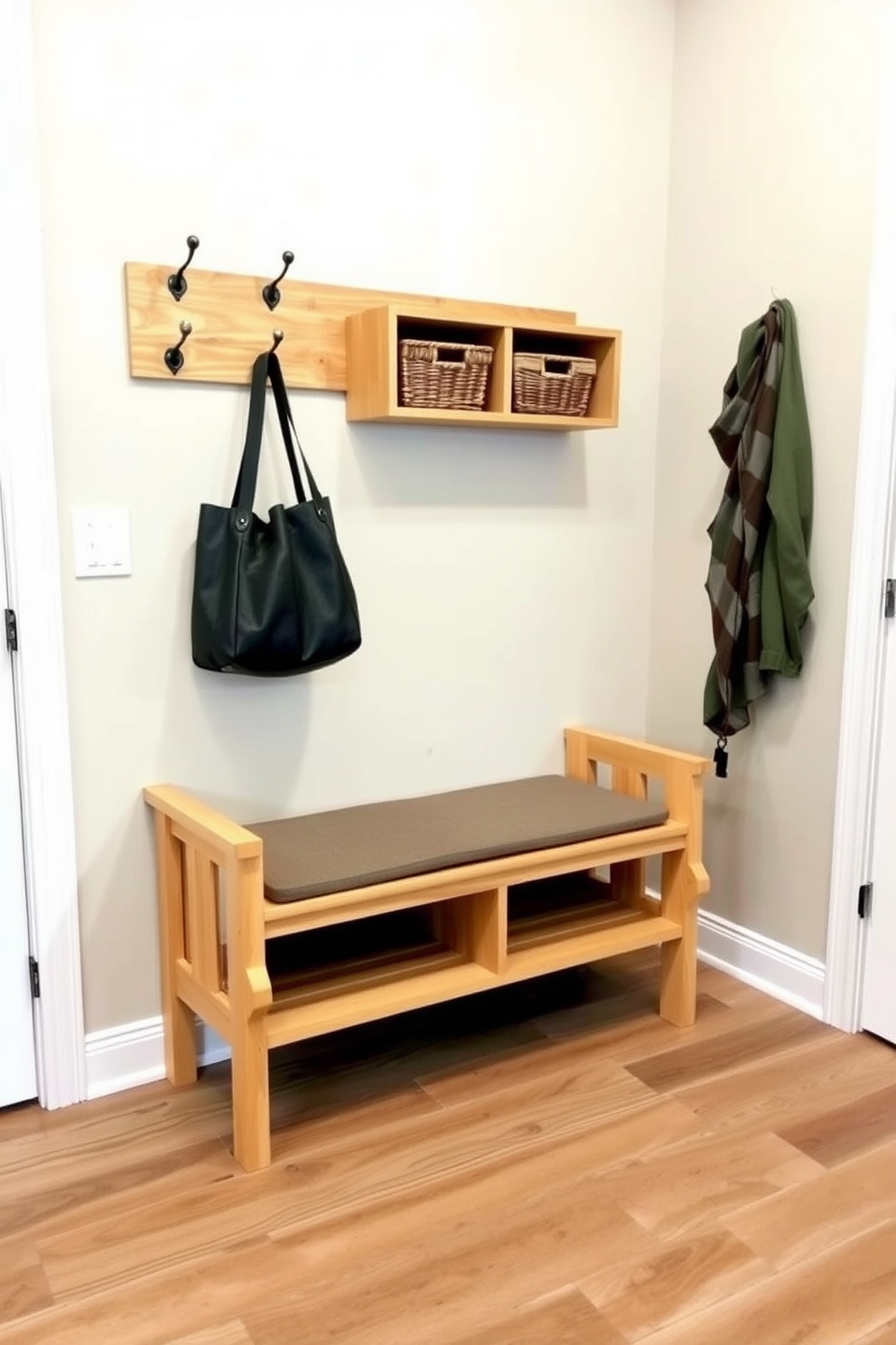 A simple bench with a natural wood finish sits against the wall of a mudroom. It features a minimalist design with clean lines and a comfortable cushion on top for added seating. Above the bench, there are hooks for hanging coats and bags, while a small shelf holds decorative baskets for storage. The floor is tiled with a durable material that complements the wood, creating a warm and inviting space.