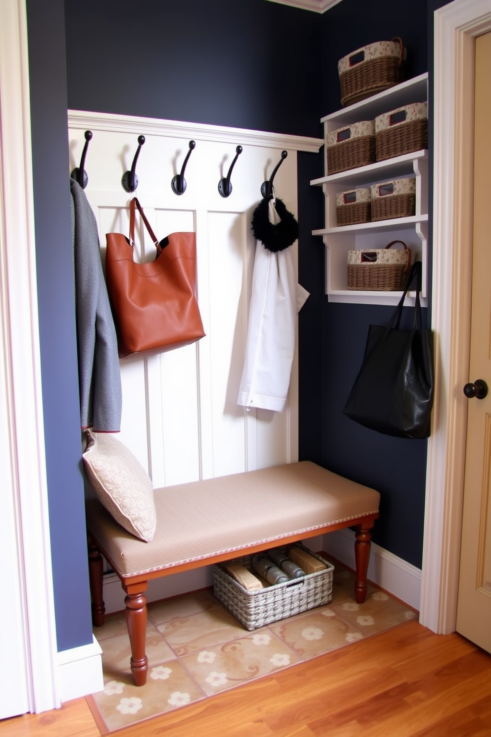 A stylish mudroom features a bench with decorative trim that enhances the overall aesthetic. The bench is upholstered in a durable fabric with a subtle pattern, providing both comfort and style. Above the bench, hooks are mounted on the wall for hanging coats and bags, while a nearby shelf holds decorative baskets for storage. The flooring is a combination of tile and wood, adding warmth and functionality to the space.