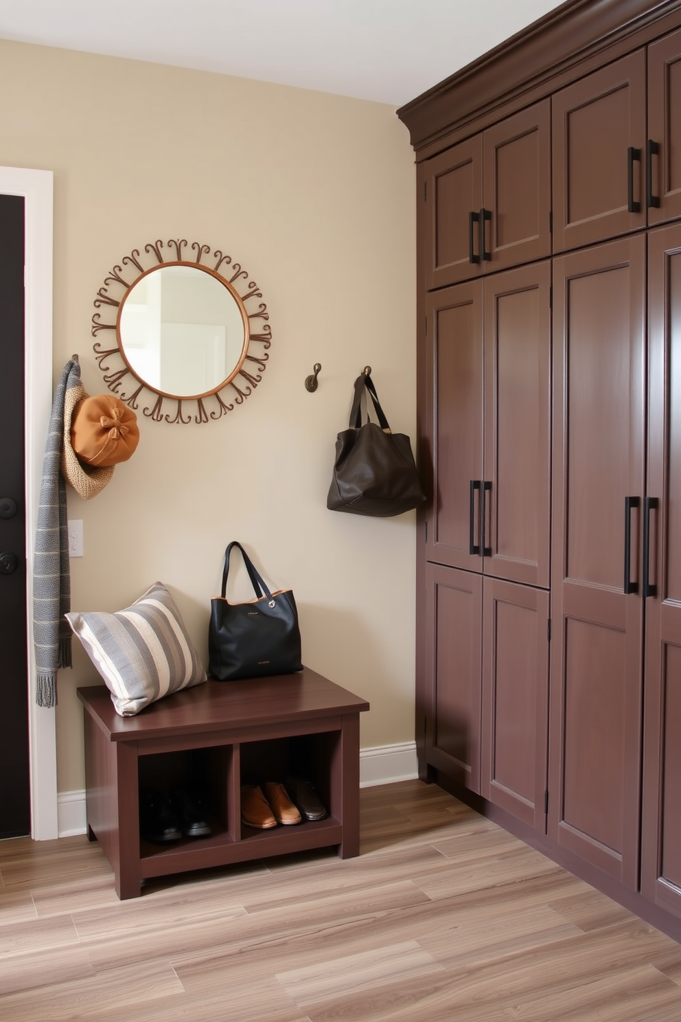 A small bench with hidden storage sits against the wall, providing a functional yet stylish seating area for putting on shoes. Above the bench, hooks are mounted for hanging coats and bags, while a decorative mirror enhances the sense of space. The mudroom features built-in cabinets on one side, offering ample storage for outdoor gear and accessories. A durable, easy-to-clean flooring complements the design, ensuring practicality in this high-traffic area.