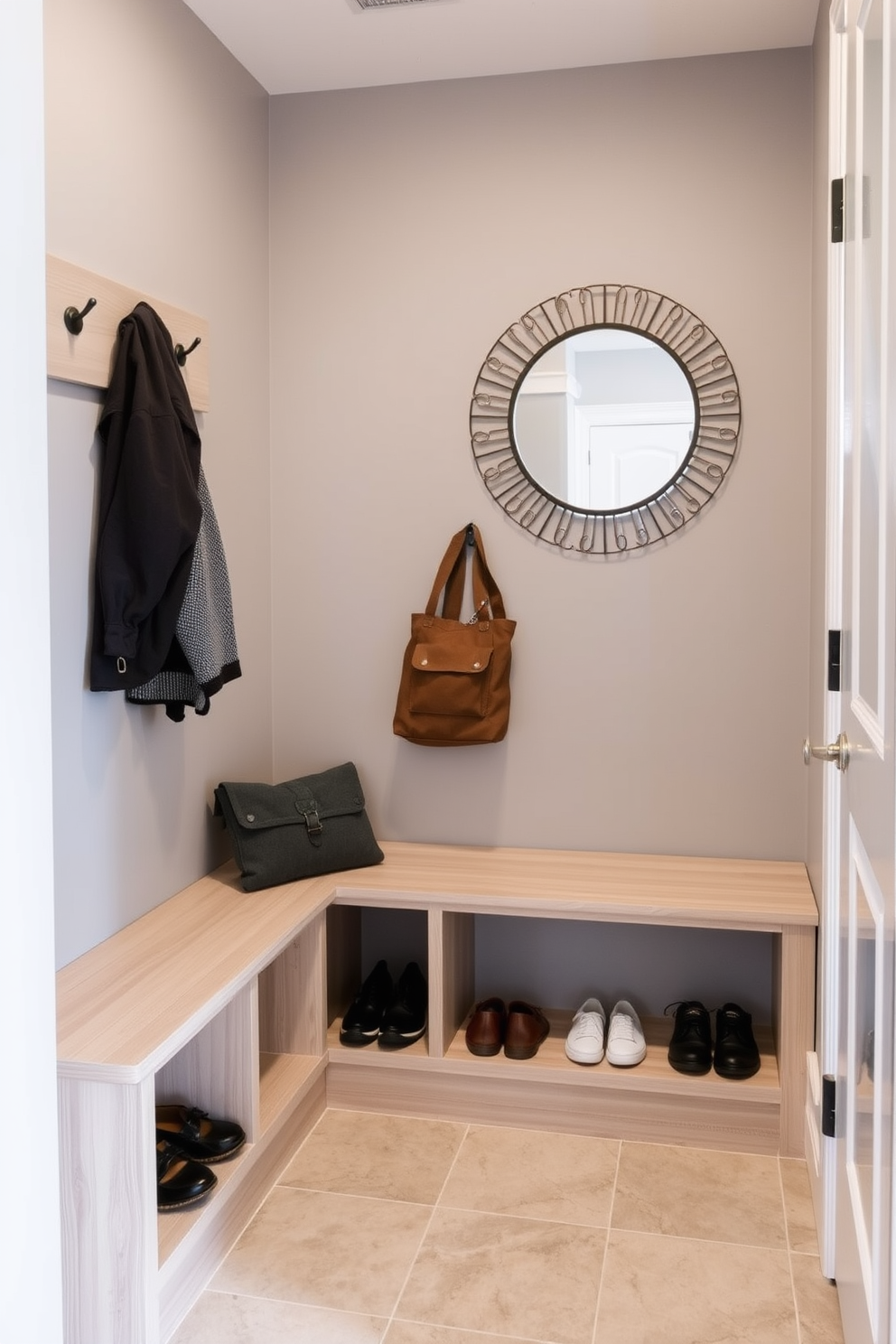 A compact mudroom design featuring built-in storage solutions to maximize space efficiency. The area includes a bench with cubbies below for shoes and a wall-mounted rack for coats, all in a light wood finish. The walls are painted a soft gray to create a calm atmosphere, while a durable tile floor adds practicality. A decorative wall mirror enhances the sense of space and functionality, making it an inviting entryway.