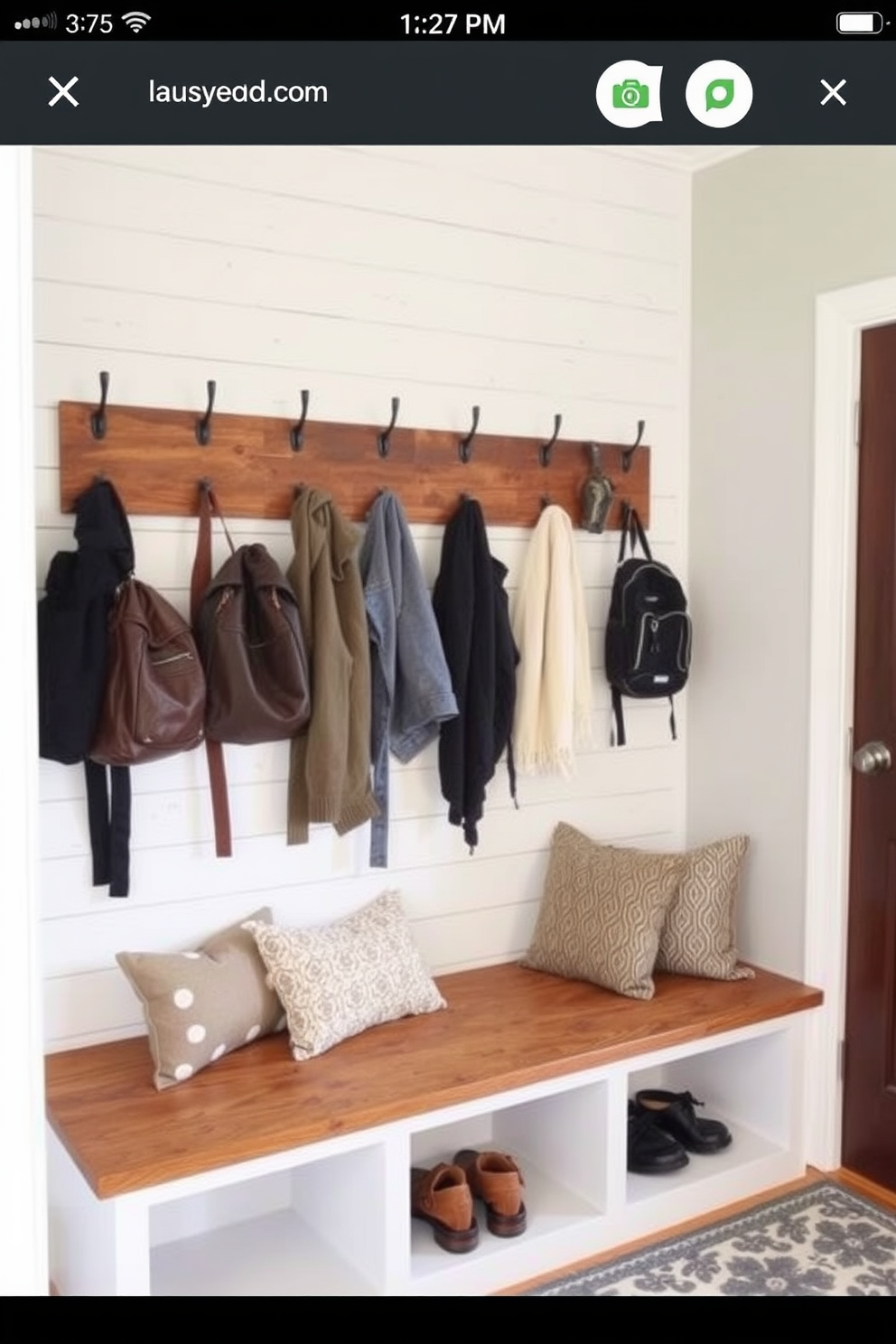 A welcoming mudroom features a row of rustic wooden hooks mounted on a shiplap wall, perfect for hanging coats and backpacks. Beneath the hooks, a built-in bench with soft cushions provides a cozy spot to sit while removing shoes, and a patterned rug adds warmth to the space.