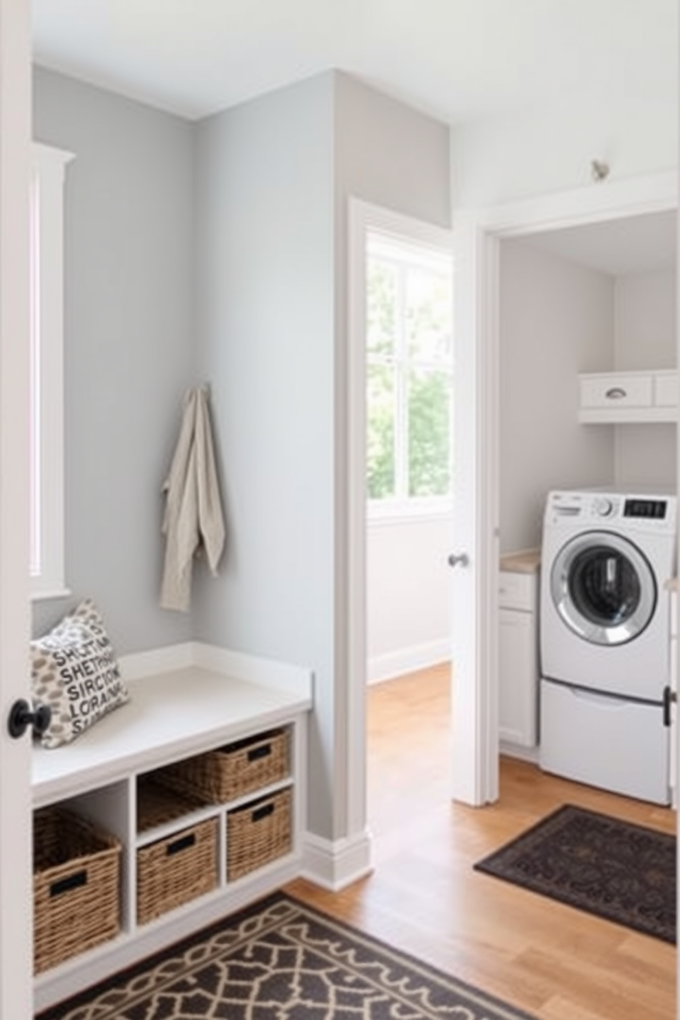 A cozy mudroom features a spacious bench with built-in storage baskets underneath for easy organization. The walls are painted in a soft gray, and a patterned rug adds warmth to the space. Adjacent to the bench, a laundry room design incorporates a sleek countertop for folding clothes and a stackable washer and dryer. Bright white cabinetry provides ample storage, while a large window allows natural light to flood the room.