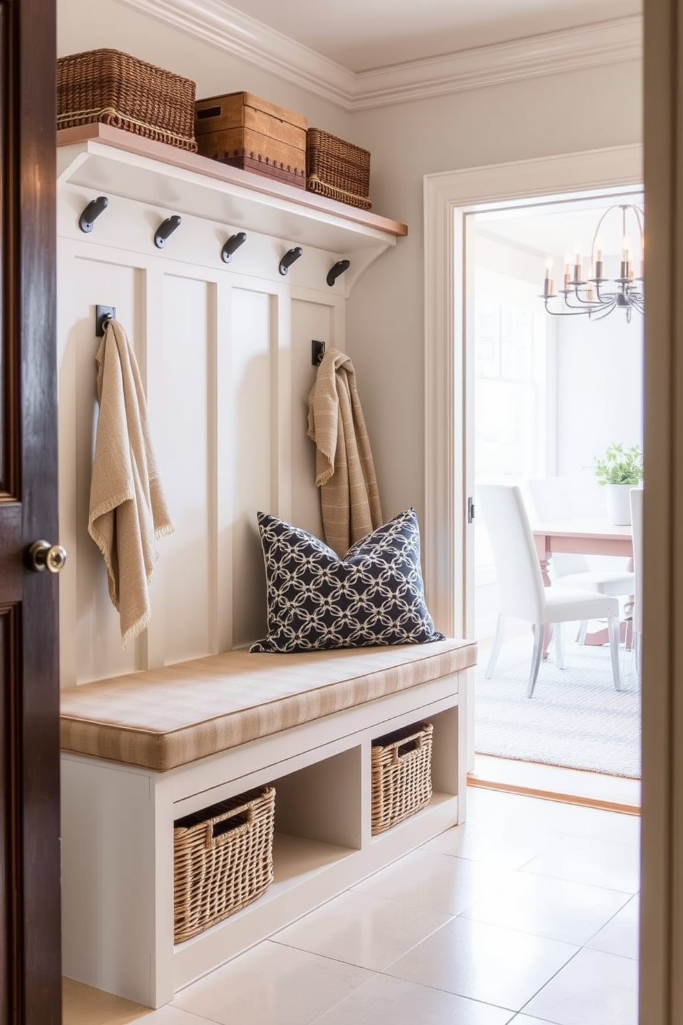 A cozy mudroom design featuring a stylish bench with ample storage underneath. The bench is upholstered in a soft fabric, complemented by decorative pillows, and is positioned near the dining room for easy access.