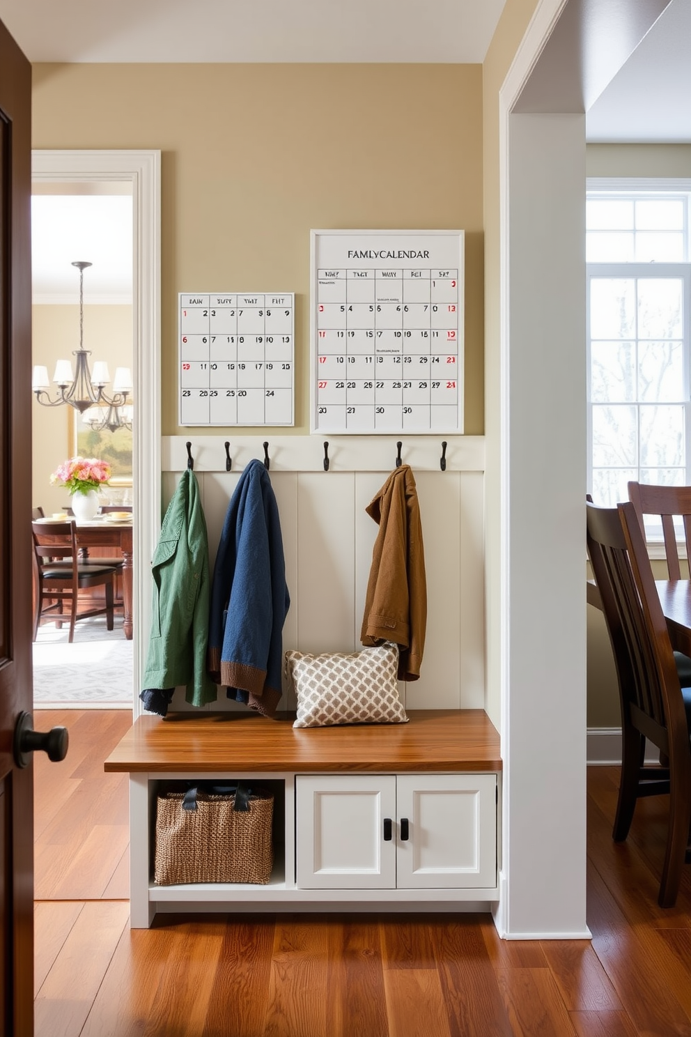 A functional family calendar is mounted on the wall in the mudroom, easily visible for everyone to see. The mudroom features built-in benches and hooks for coats, creating an organized and inviting space. Adjacent to the dining room, the mudroom is designed with a warm color palette that complements the dining area. Natural light floods in through a nearby window, enhancing the welcoming atmosphere.