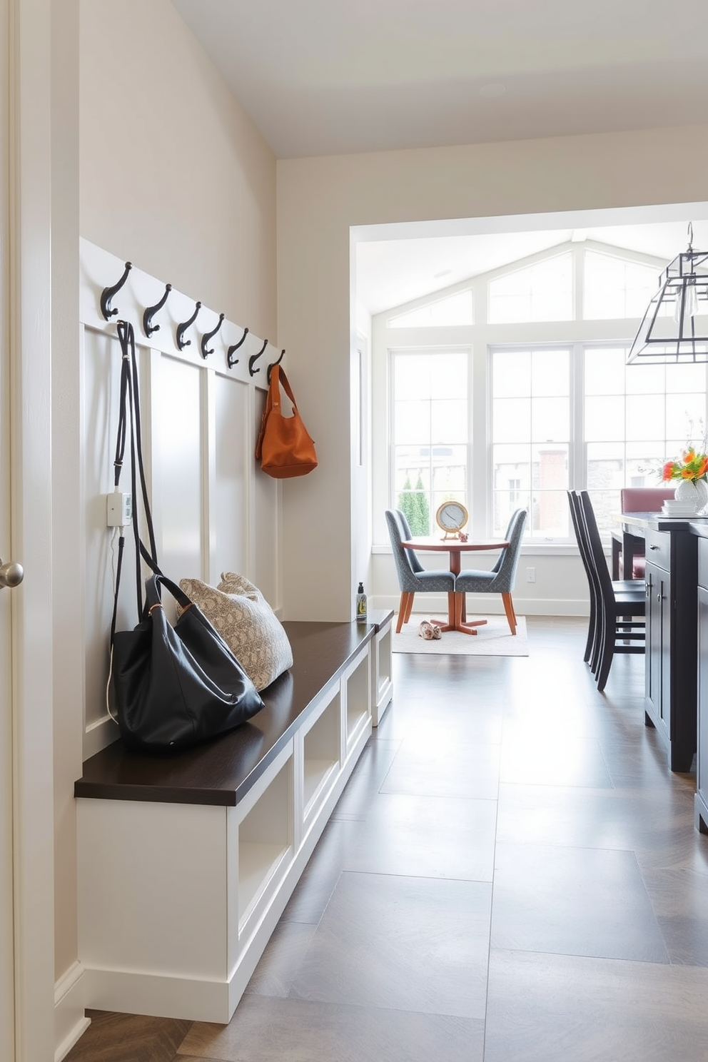 A functional drop zone is designed with a sleek bench and built-in hooks for coats and bags. The charging station is integrated into the bench, featuring multiple outlets and USB ports for easy access. The mudroom is spacious and features durable flooring that can withstand heavy foot traffic. Natural light floods the area through a large window, creating an inviting atmosphere near the dining room.