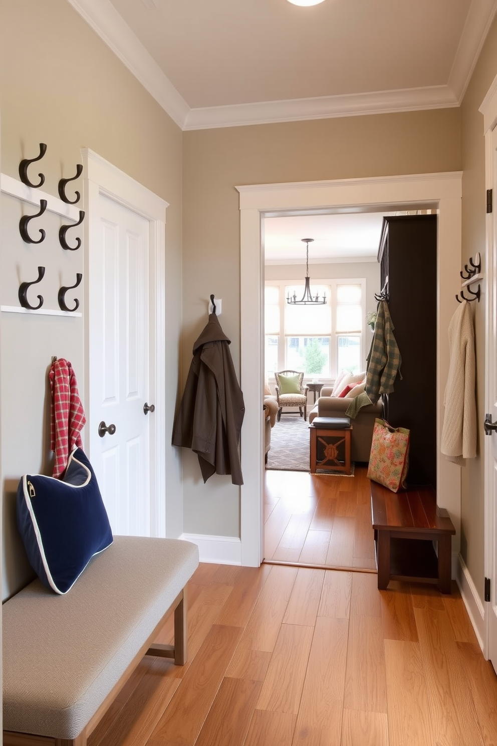 A welcoming mudroom adjacent to the family room features an array of stylish wall hooks for quick coat hanging. The walls are painted in a soft beige, complemented by a durable hardwood floor and a cozy bench for added comfort.