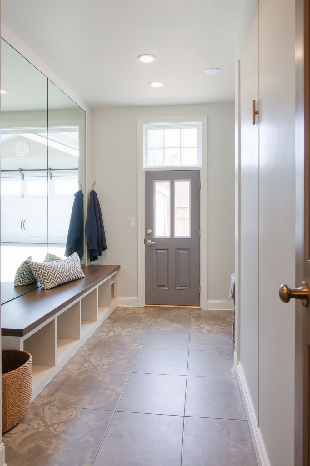 A welcoming mudroom near the garage features a large mirror that reflects natural light, creating an airy and bright atmosphere. The space includes built-in storage benches and hooks for coats, with a stylish tile floor that is both functional and easy to clean.