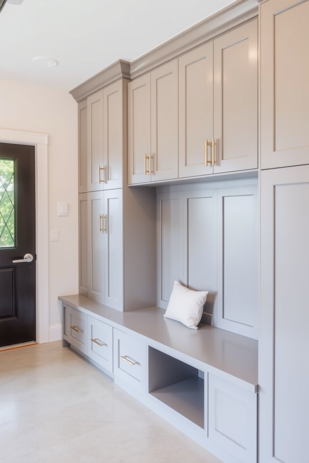 Custom cabinetry for a sleek look in a mudroom near the garage features floor-to-ceiling storage solutions with a minimalist aesthetic. The cabinetry is painted in a soft gray hue, complemented by polished nickel hardware and a built-in bench for convenience.