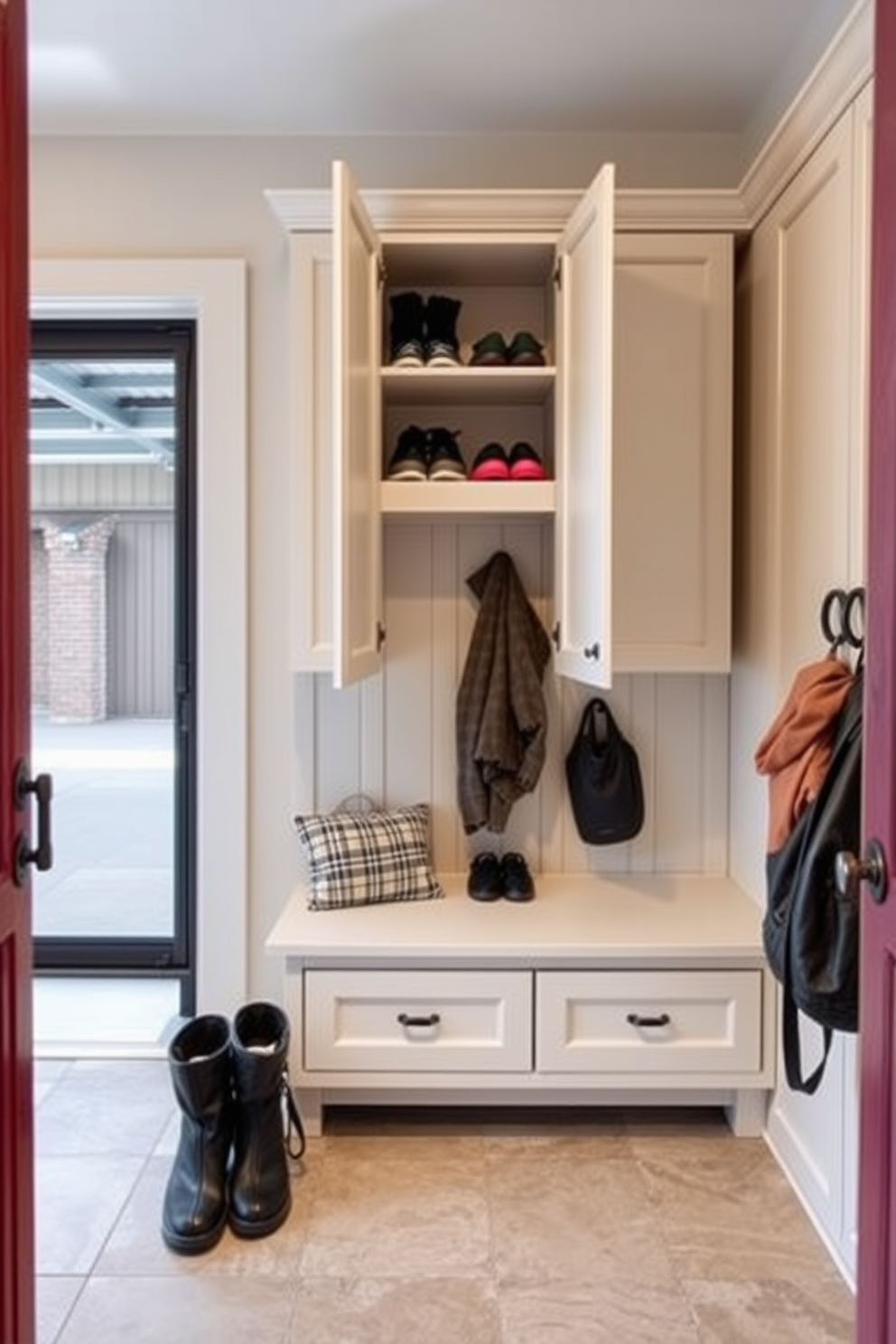 A functional mudroom near the garage features built-in cabinetry with hidden compartments to store shoes and outdoor gear. The space is designed with a durable tile floor and a bench for convenience, accented by hooks for coats and bags.