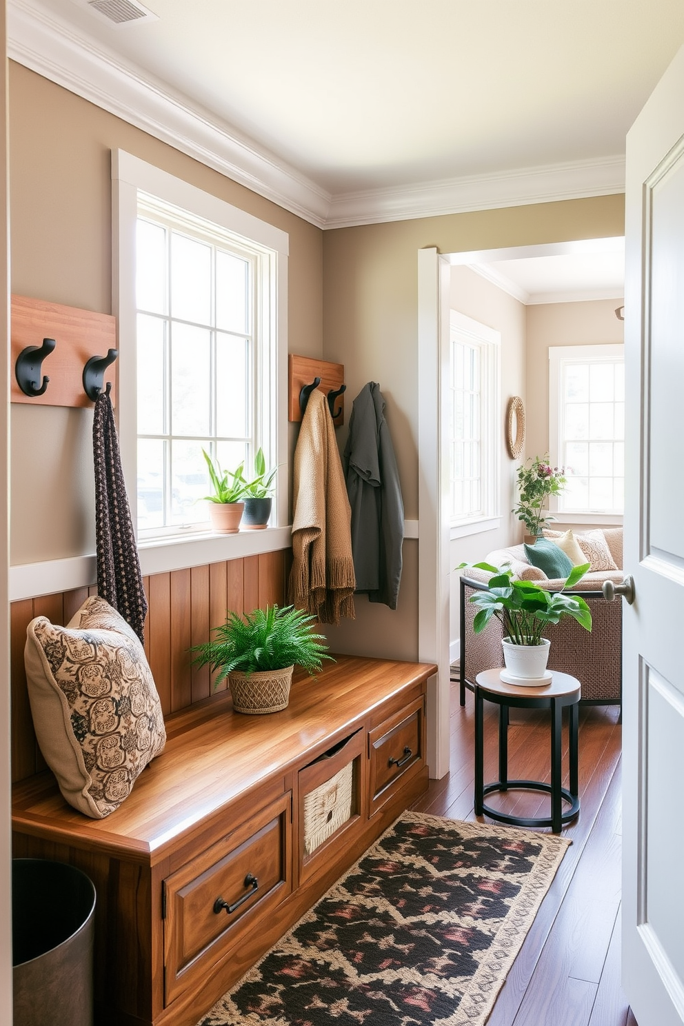 A welcoming mudroom design that seamlessly connects to the living room. The space features built-in wooden benches with plush cushions and hooks for coats, complemented by potted plants adding a touch of nature. Natural light floods the area through a large window, enhancing the earthy tones of the decor. A patterned area rug lies beneath the benches, providing warmth and texture to the space.