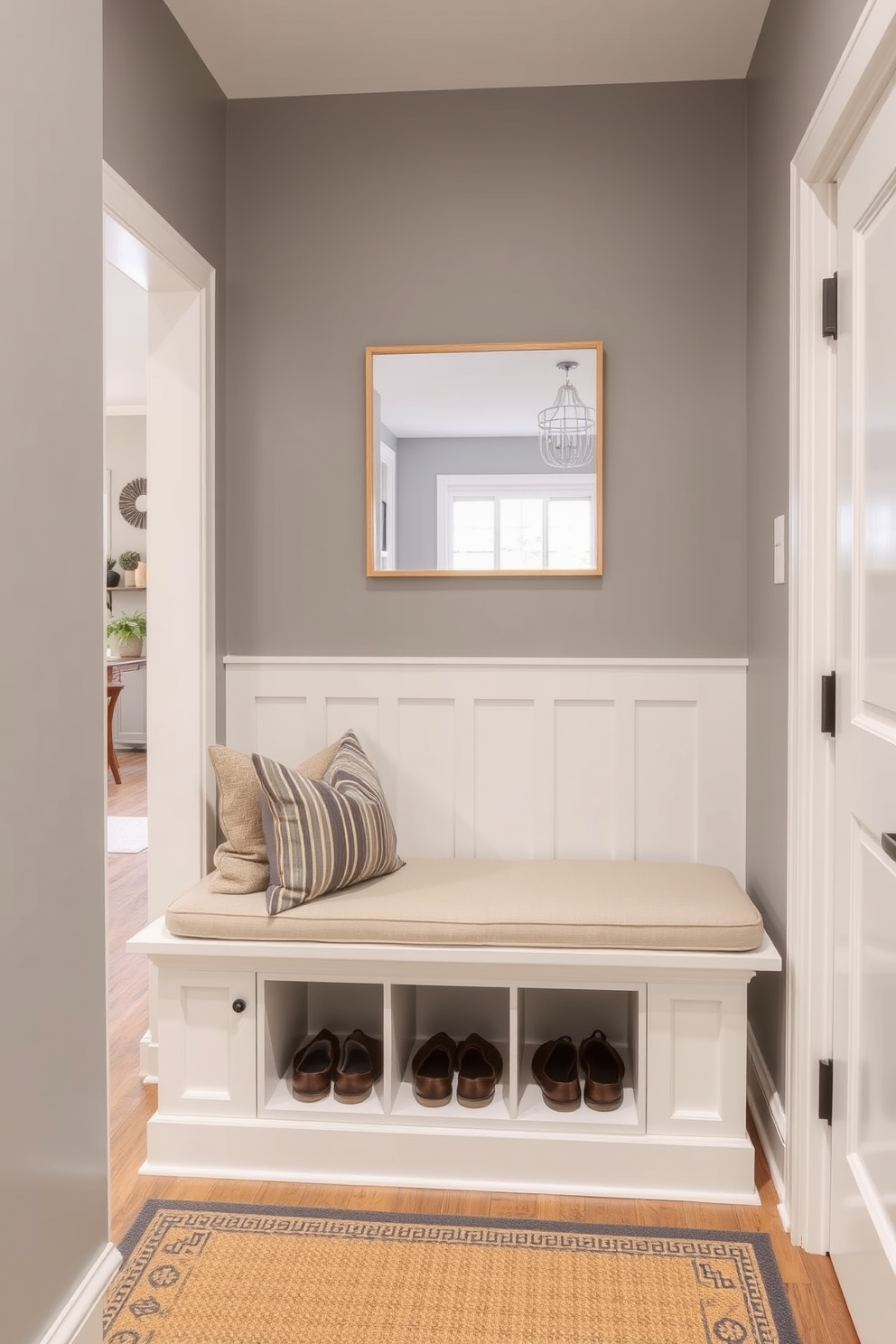 A welcoming mudroom features a built-in bench with ample shoe storage underneath. The bench is adorned with plush cushions, and the walls are painted in a soft gray hue, creating a cozy transition space near the living room.