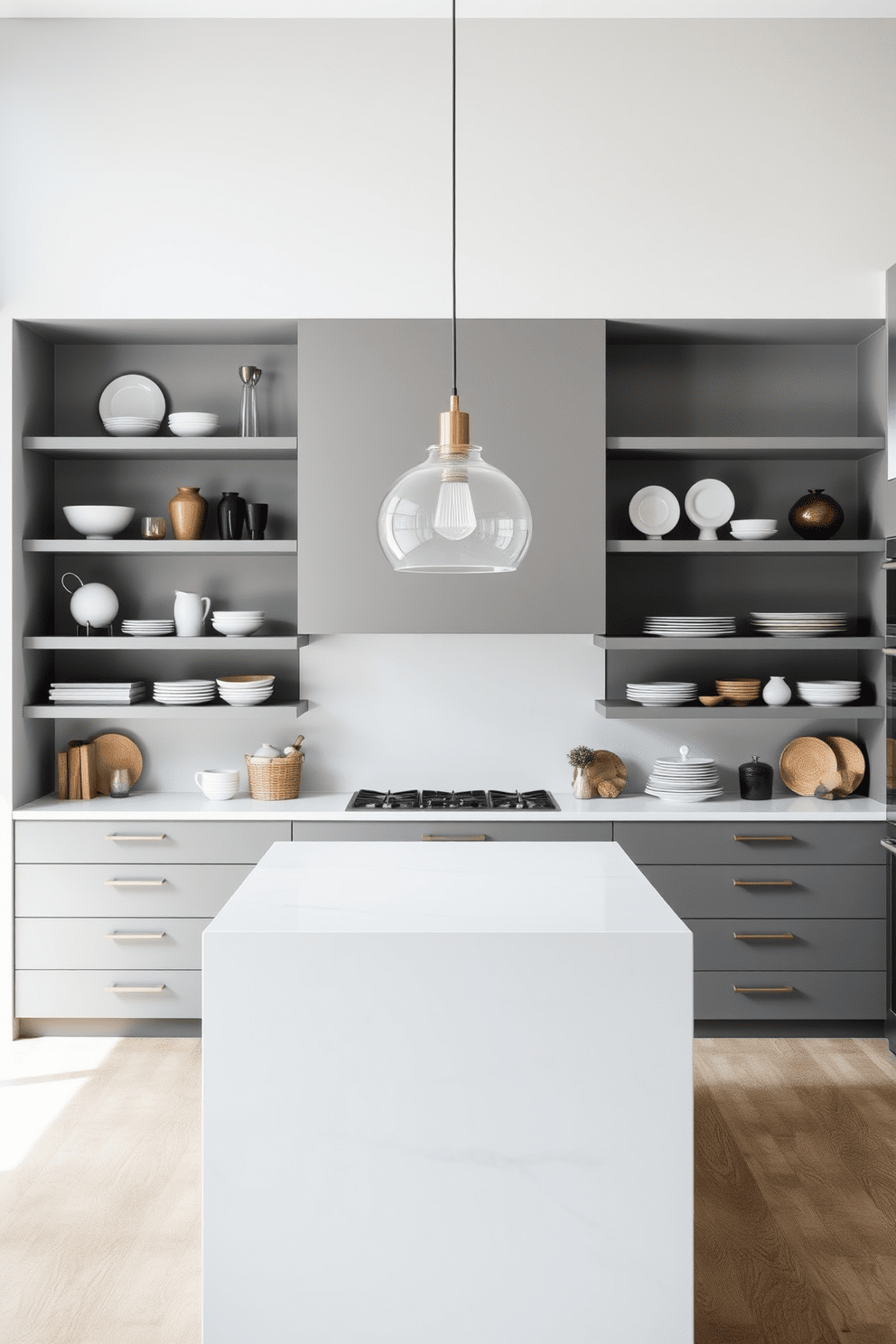 A modern kitchen featuring open shelving that showcases a curated collection of dishware and decorative items. The cabinetry is sleek and minimalistic, with a large island at the center topped with a white quartz surface. The walls are painted in a soft gray tone, creating a bright and airy atmosphere. A stylish pendant light hangs above the island, adding a touch of elegance to the space.