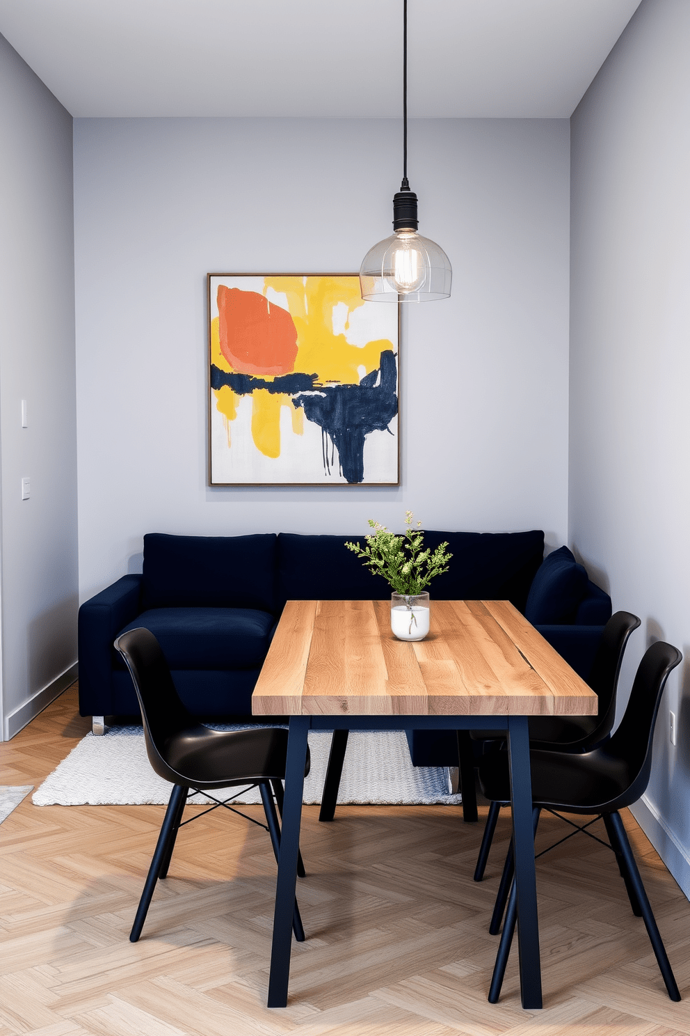 A narrow apartment design featuring a sleek sectional sofa in a rich navy blue, positioned against a light gray accent wall. A large piece of abstract art hangs above the sofa, drawing the eye and adding a burst of color to the space. Incorporate a minimalist dining table made of reclaimed wood, paired with modern black chairs. A pendant light with an industrial design hangs above the table, providing both illumination and a stylish focal point.