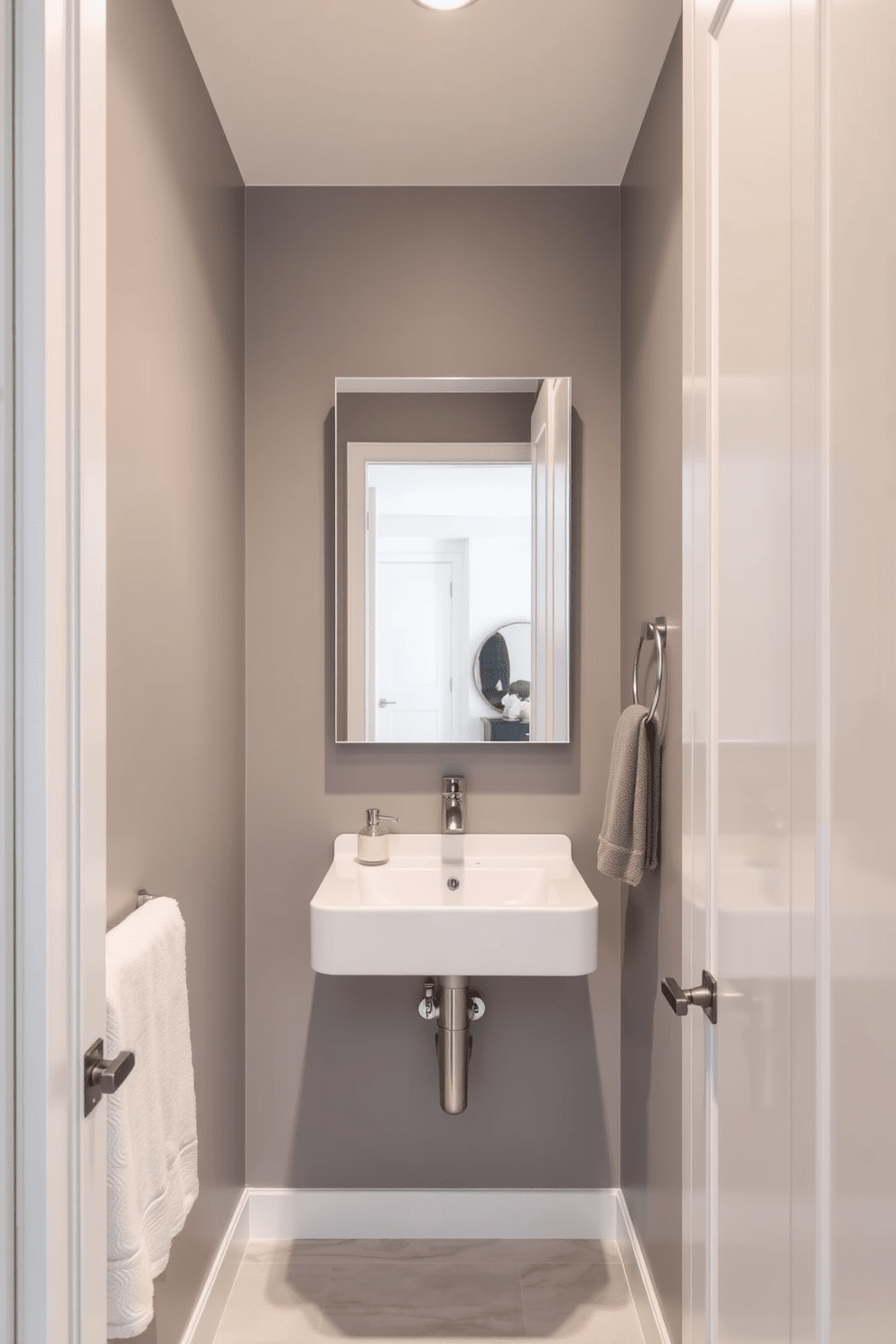 A narrow bathroom design featuring a corner sink to maximize space. The walls are painted in a soft gray, complemented by sleek white cabinetry and a large mirror that enhances the sense of openness.