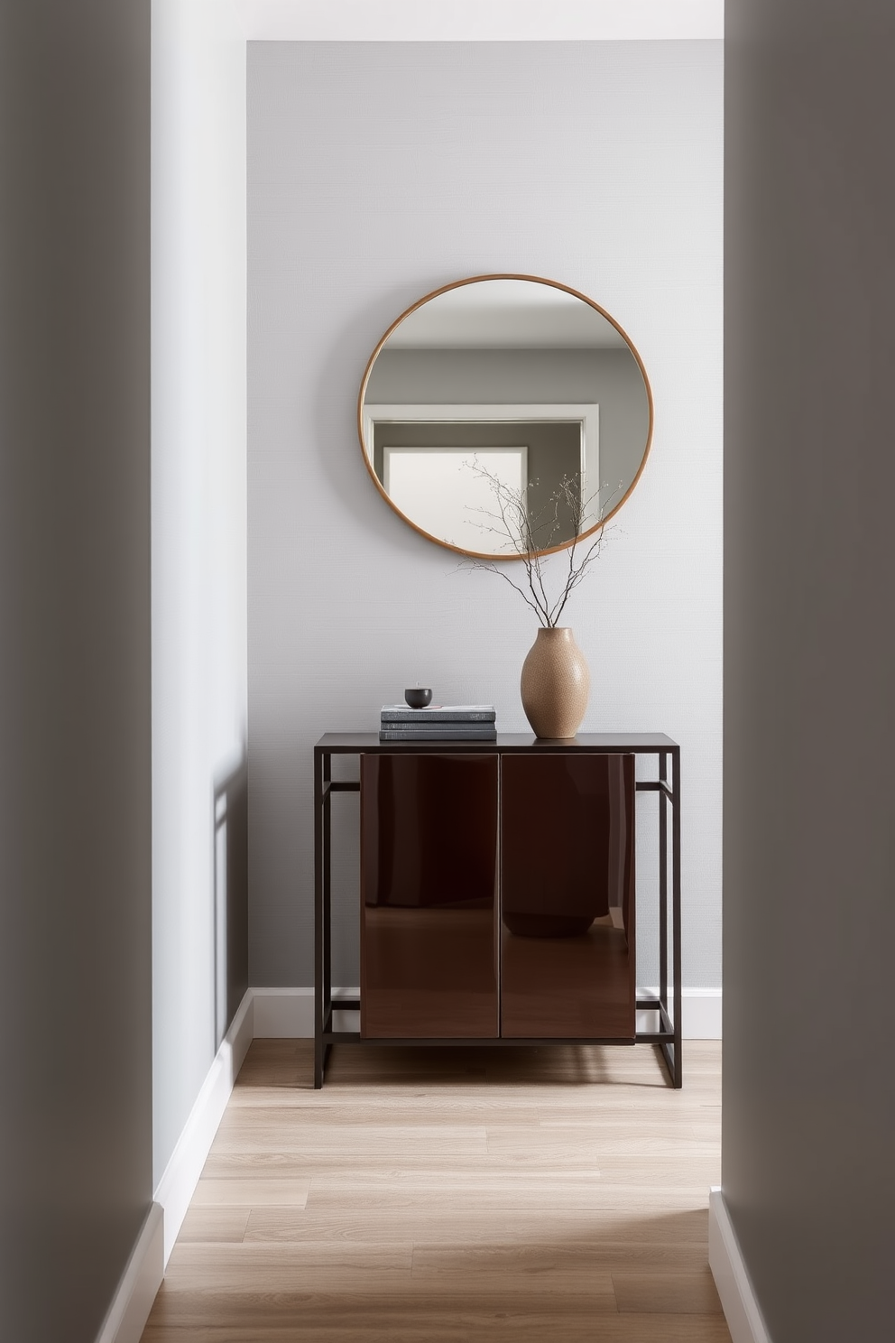 A narrow entryway featuring a sleek, tall cabinet with a glossy finish for extra storage. The walls are painted in a soft gray with a subtle texture, complemented by a minimalist console table and a large round mirror above it.