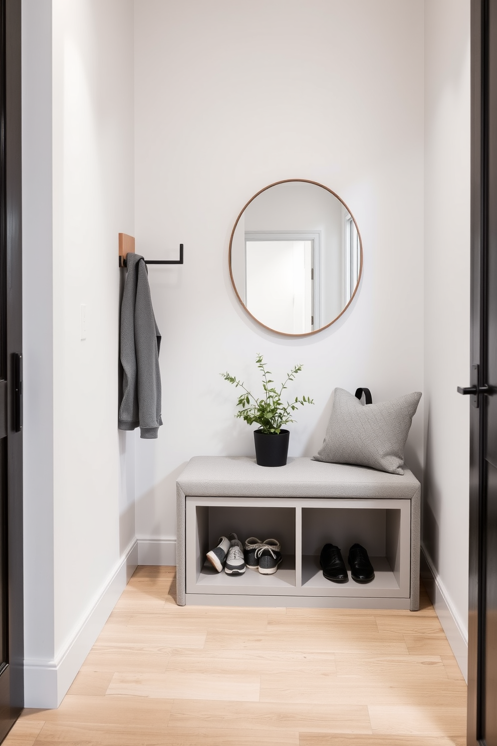 A narrow entryway features a sleek bench designed for both seating and storage. The bench is upholstered in a soft gray fabric with hidden compartments underneath, perfect for stowing away shoes and accessories. The walls are painted in a light, airy color to enhance the space, and a minimalist coat rack is mounted beside the bench. A small potted plant adds a touch of greenery, while a statement mirror above the bench creates an illusion of depth in the narrow hallway.